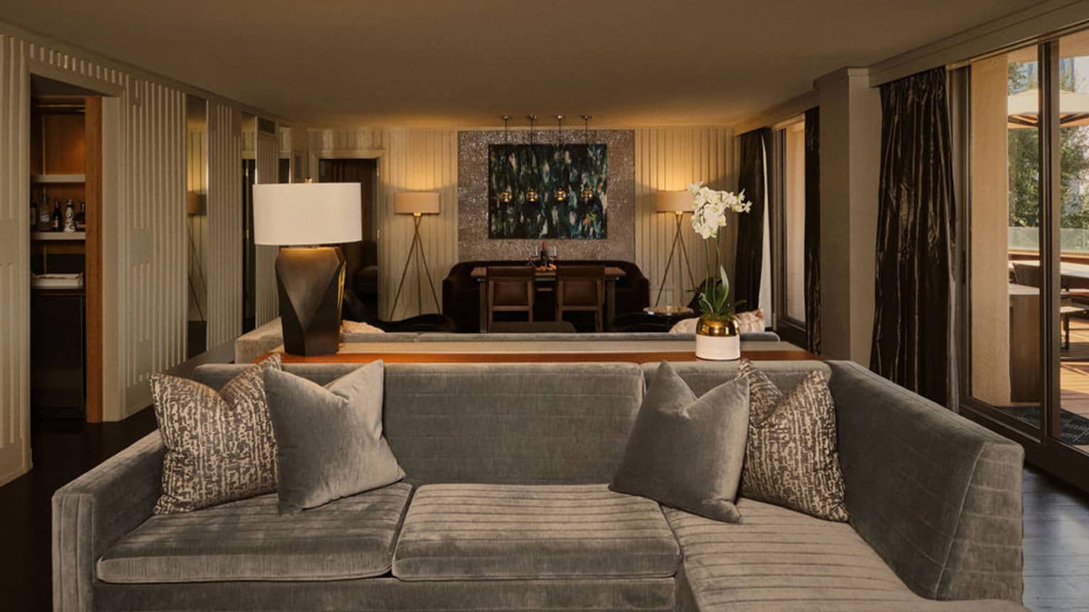 Contemporary hotel suite featuring a grey sofa and walk-out terrace