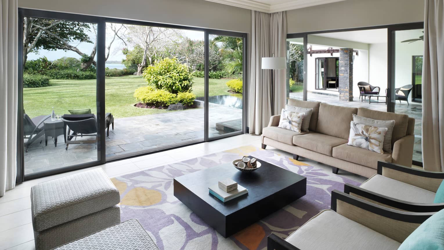 Deluxe Residence Villa bright living room, glass wall sliding door to stone patio, lawn