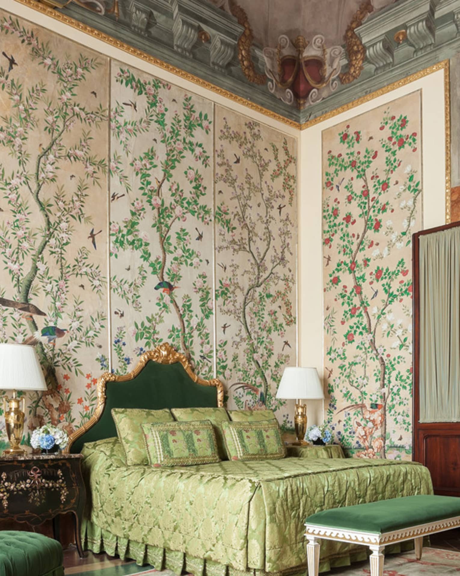 Hotel room with bed, green velvet chair and bench, antique garden wallpaper