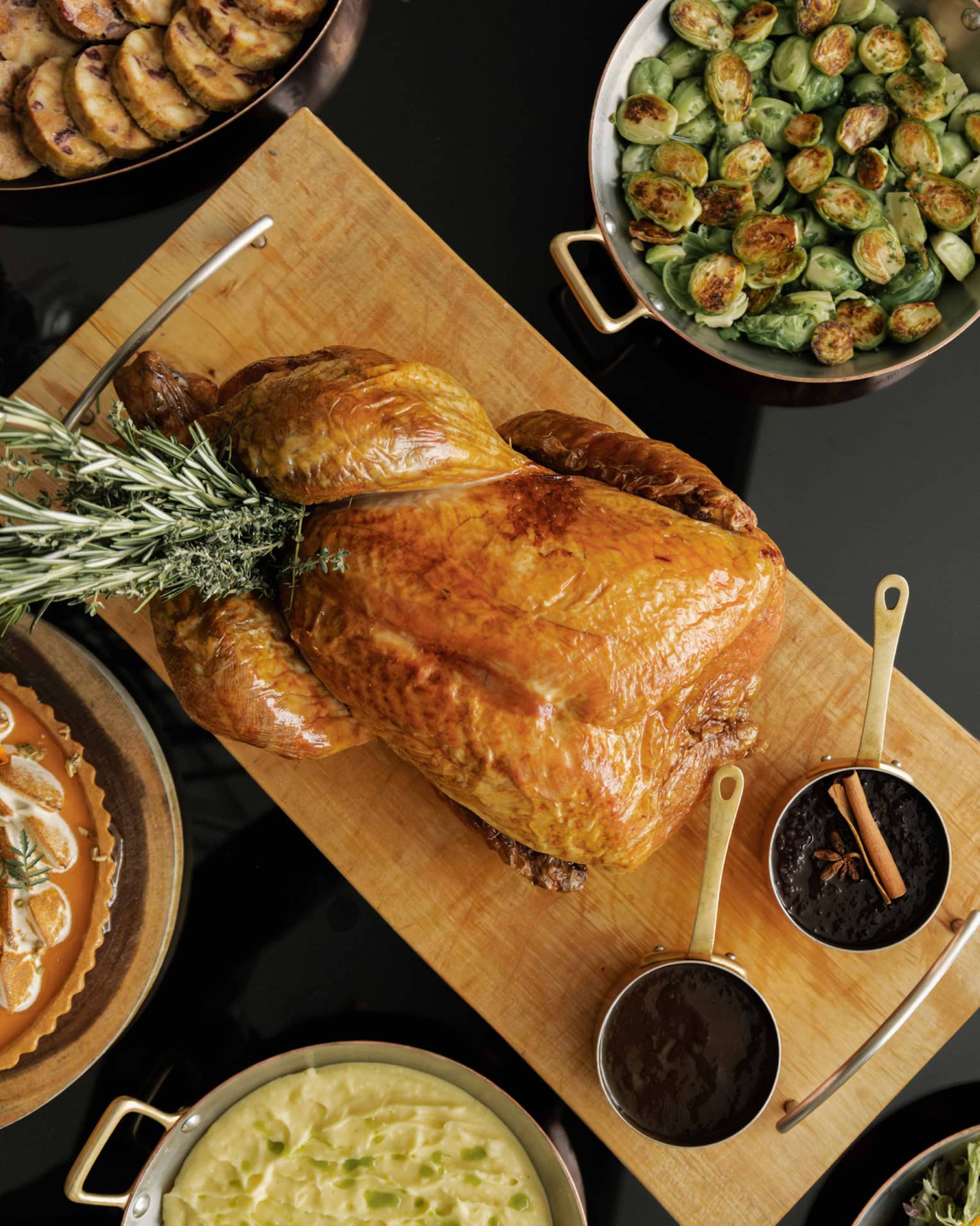 Table set with a roasted turkey, Brussels sprouts, sliced carrots and various other dishes for a holiday meal,Table set with a roasted turkey, Brussels sprouts, clived carrots and various other dishes for a holiday meal