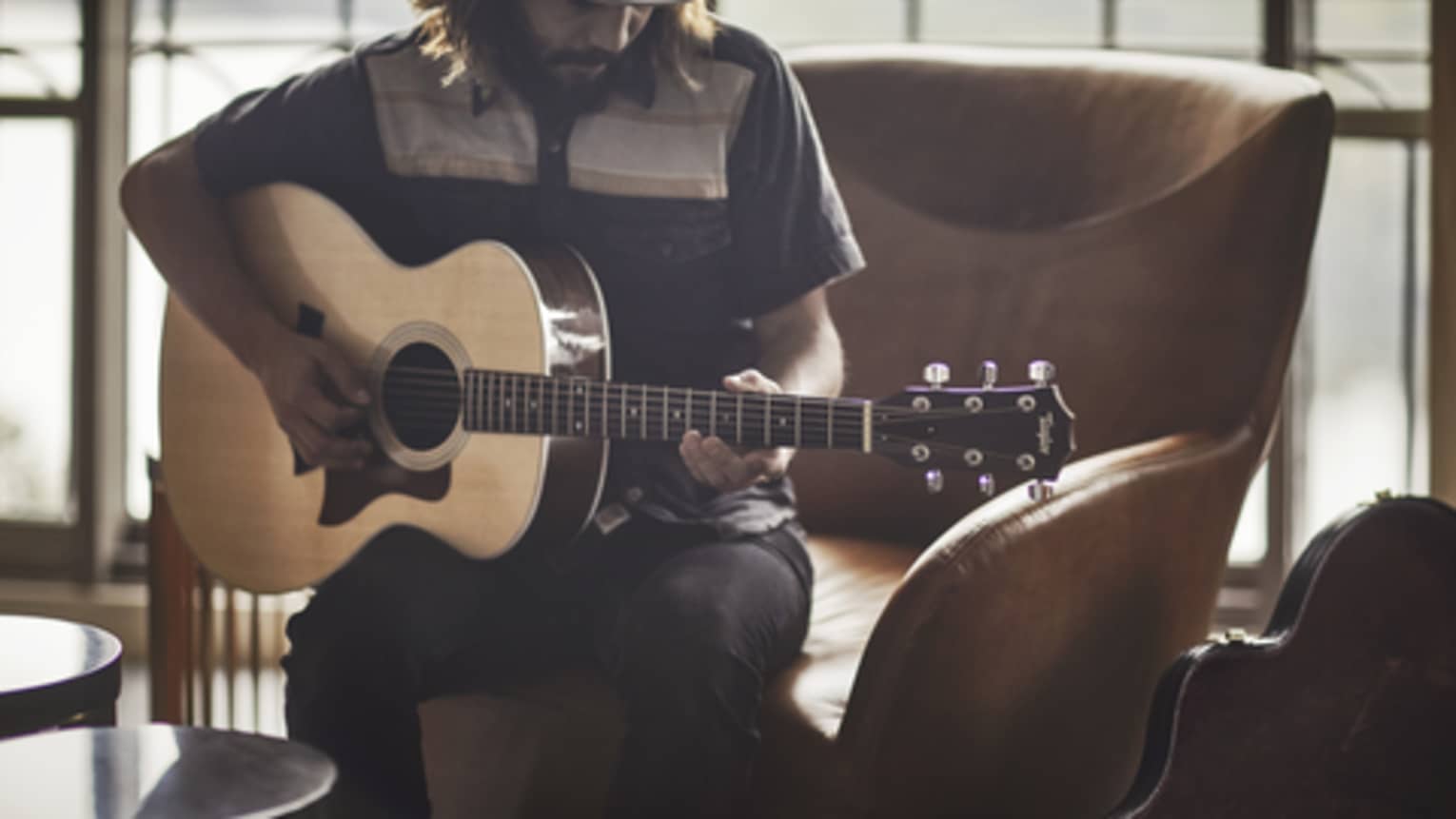 Guitar Concierge plays Taylor acoustic guitar on modern armchair