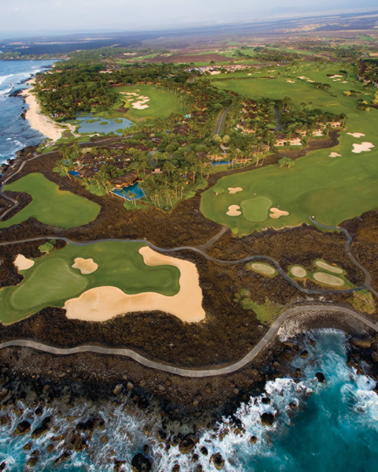 Aerial view of Hualalai Golf Course along rocky shore and ocean