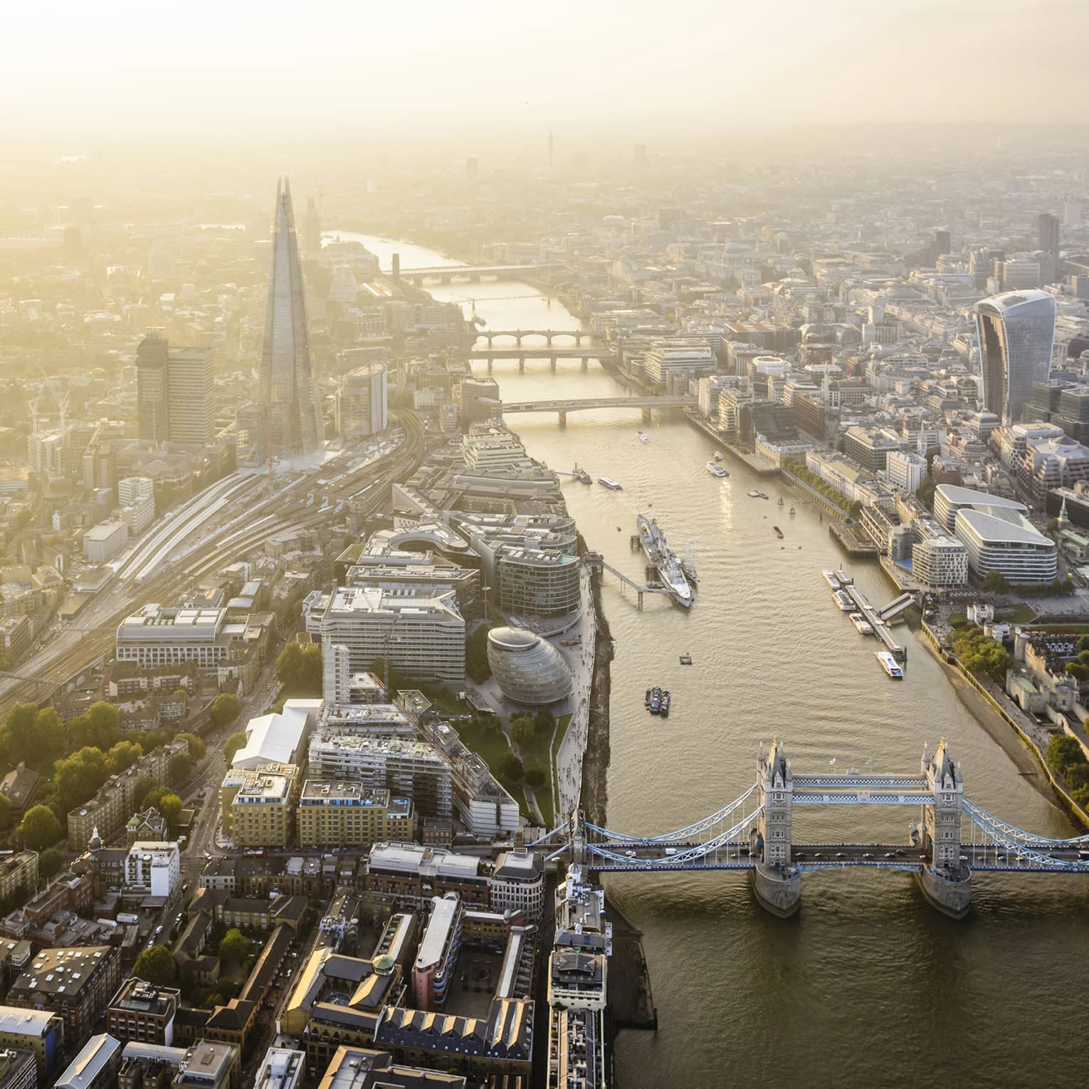 Aerial view of London city buildings along River Thames, London bridge in foreground 