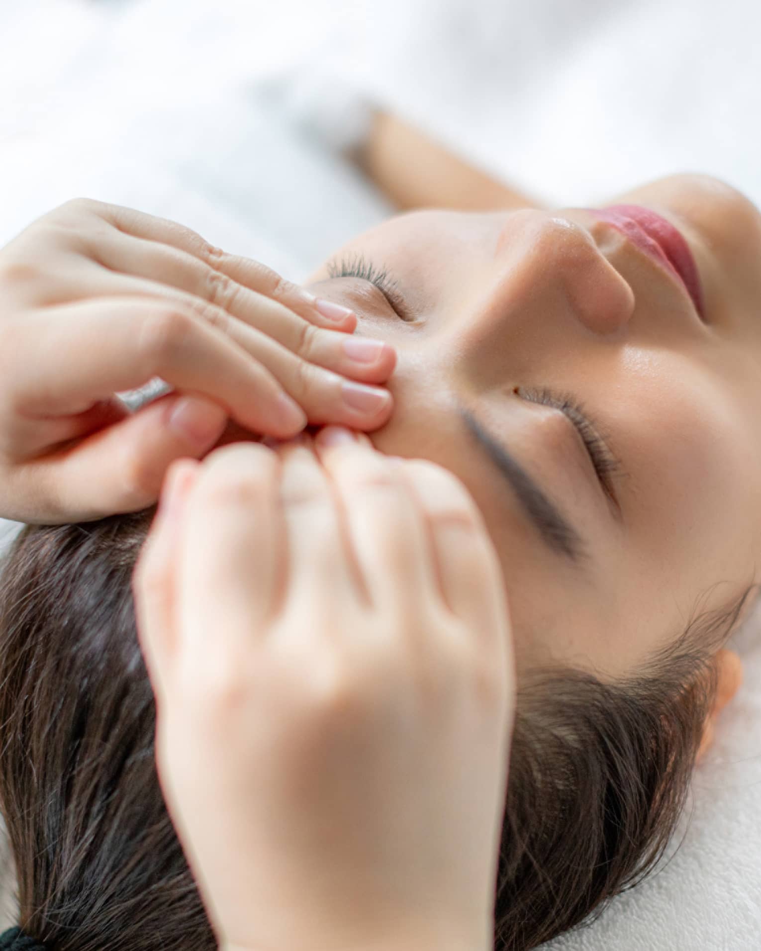 A woman getting a facial massage in a spa.
