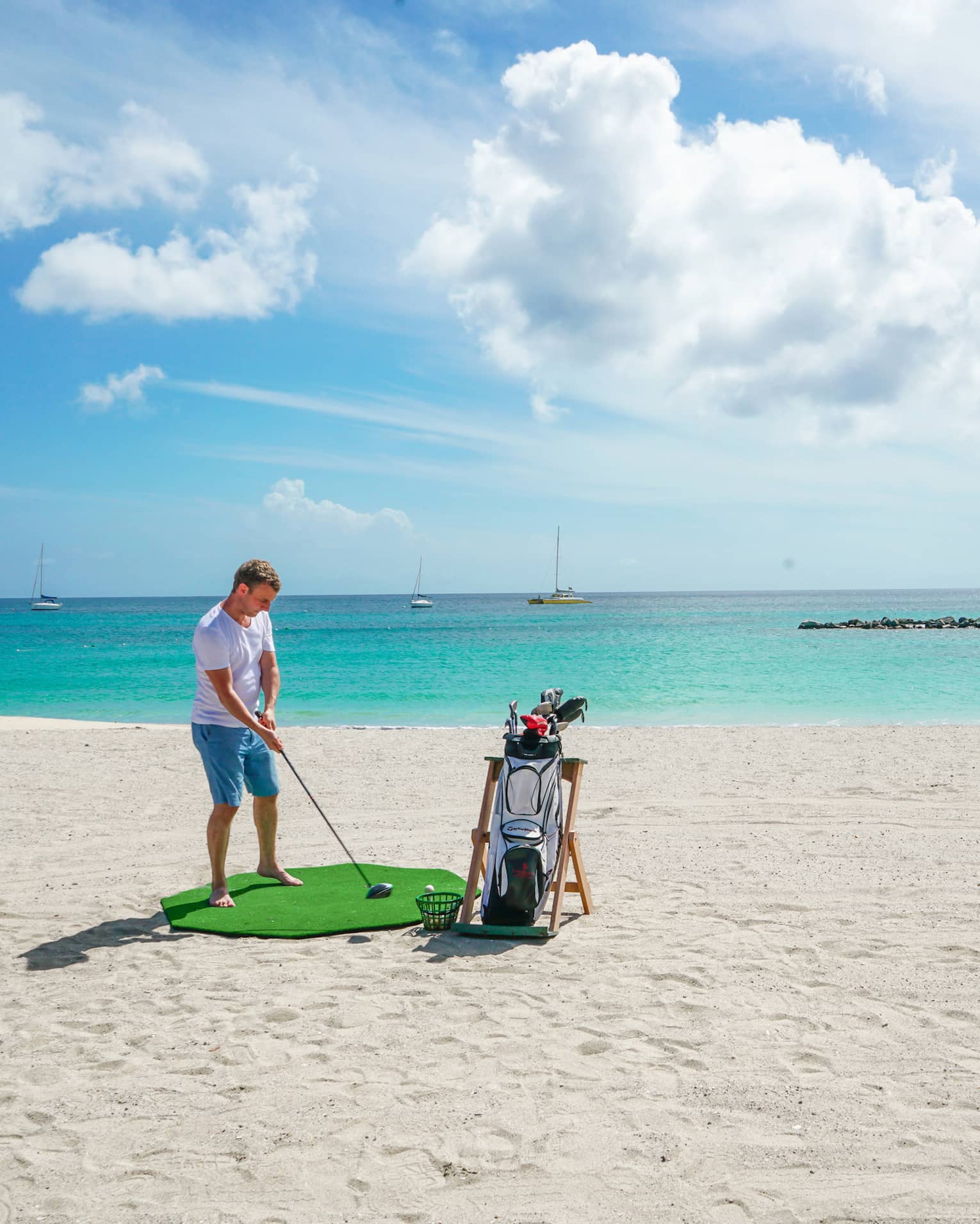 A man golfing on a clean beach near the ocean.