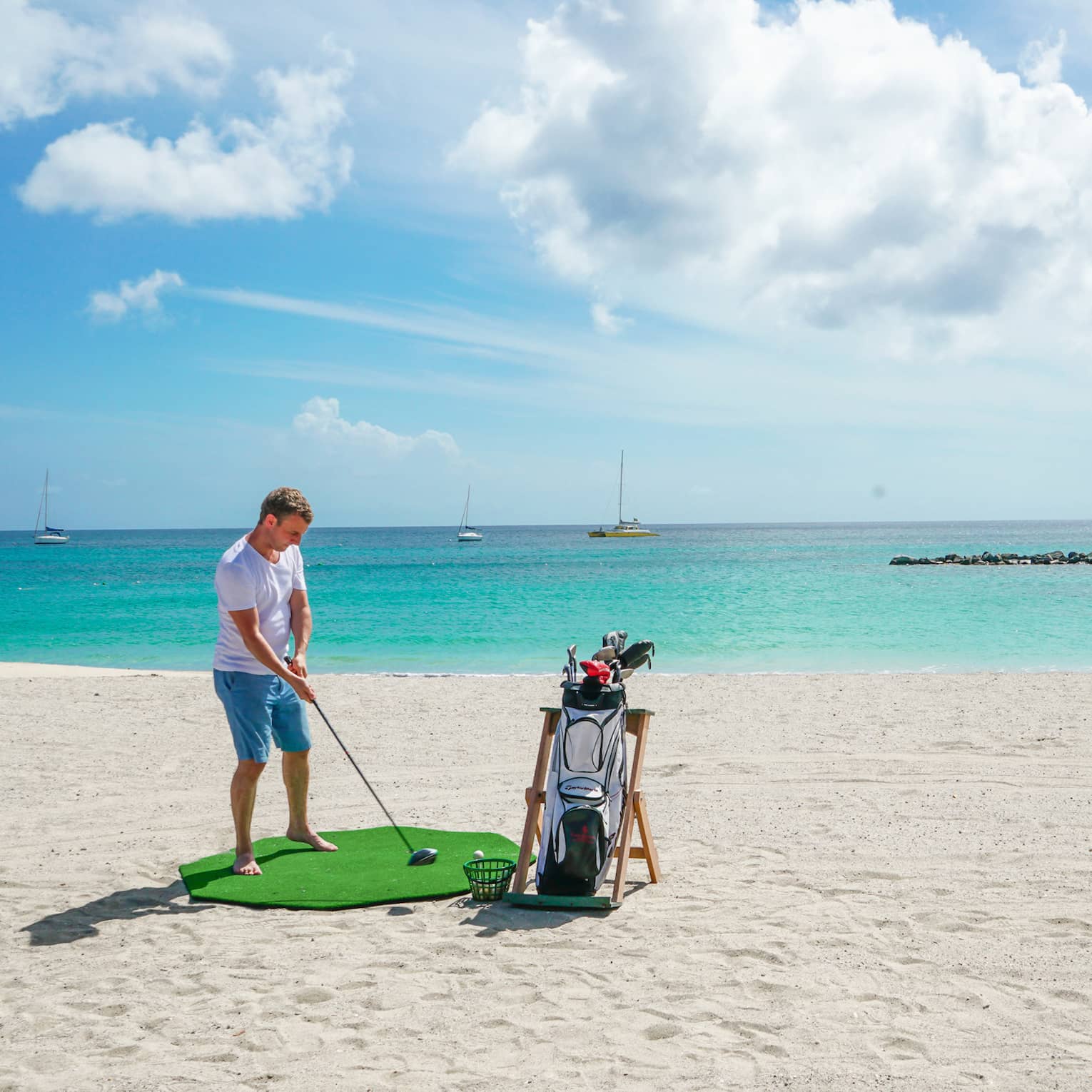 A man golfing on a clean beach near the ocean.