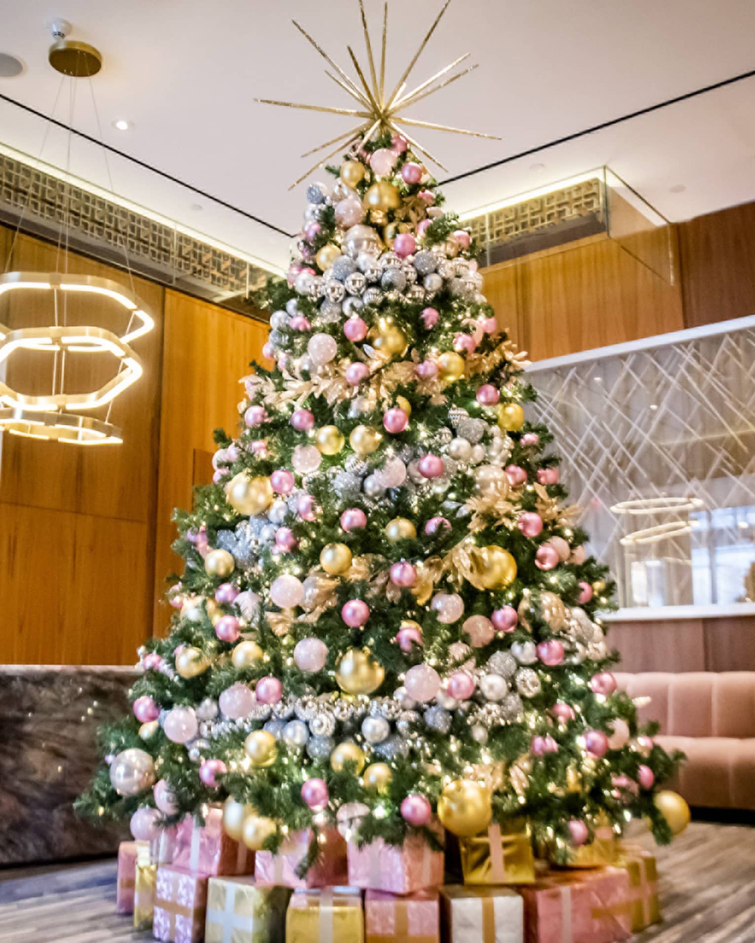 Christmas tree decorated in gold and pink in lobby at Four Seasons Toronto, pink sofa and large framed art in background