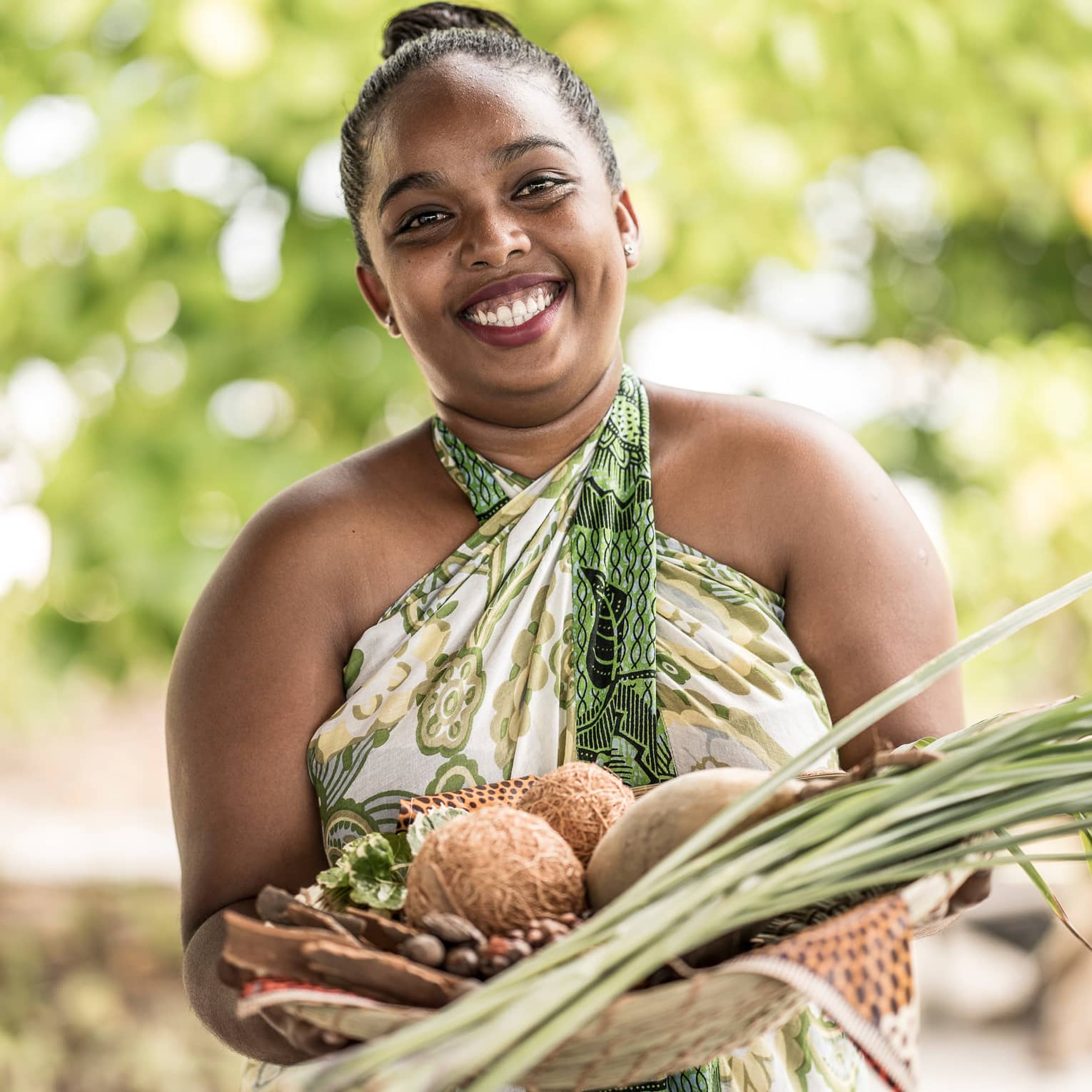 Smiling woman holds spa basket with coconuts, lemongrass, herbs