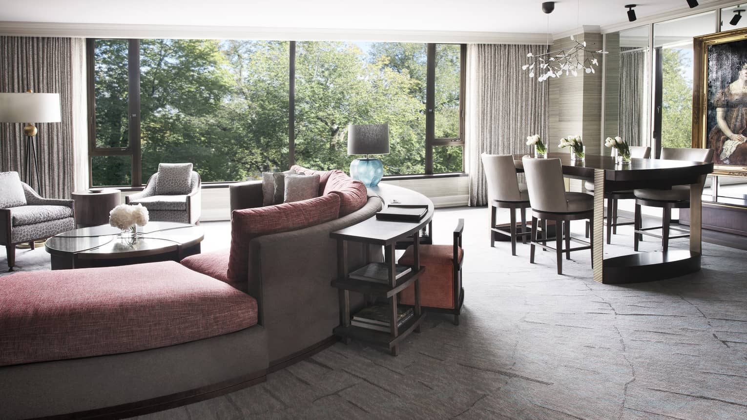 Large, bright hotel Garden Suite with curved plush sofa and armchairs, dining table
