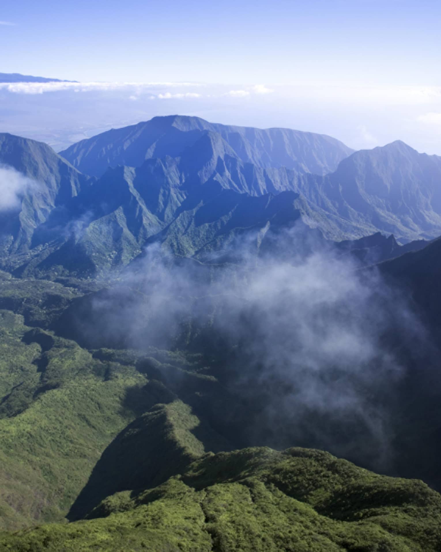 Clouds hover over green volcanic mountains