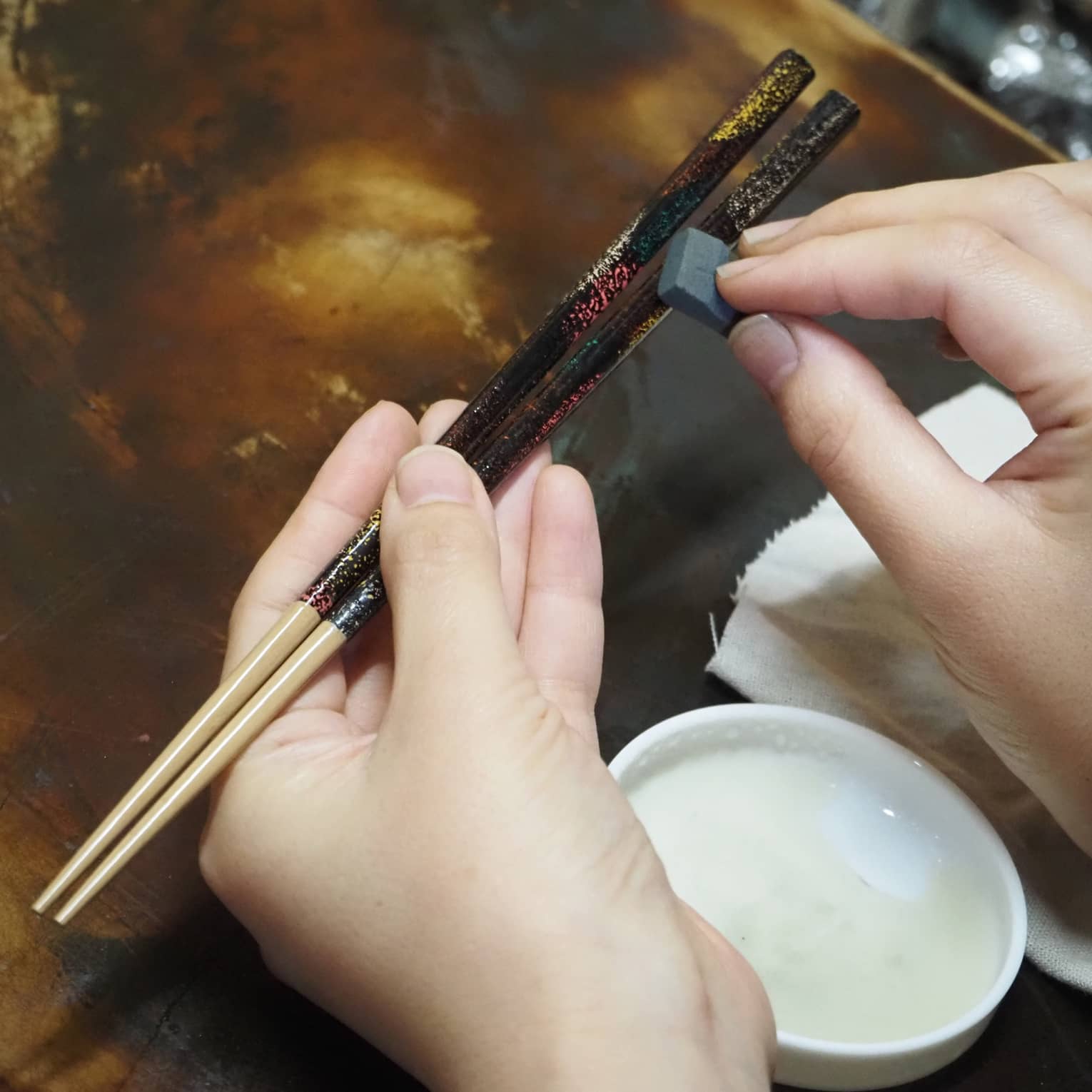 Hands apply Japanese lacquer to customize artisan chop sticks