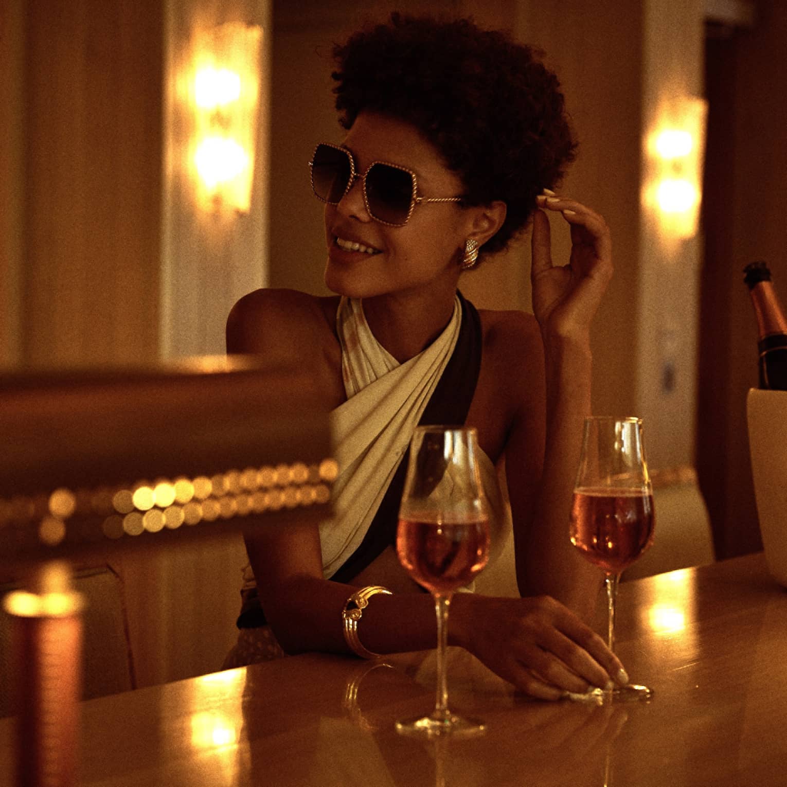 A woman sitting a dimly lit bar with a glass of wine.