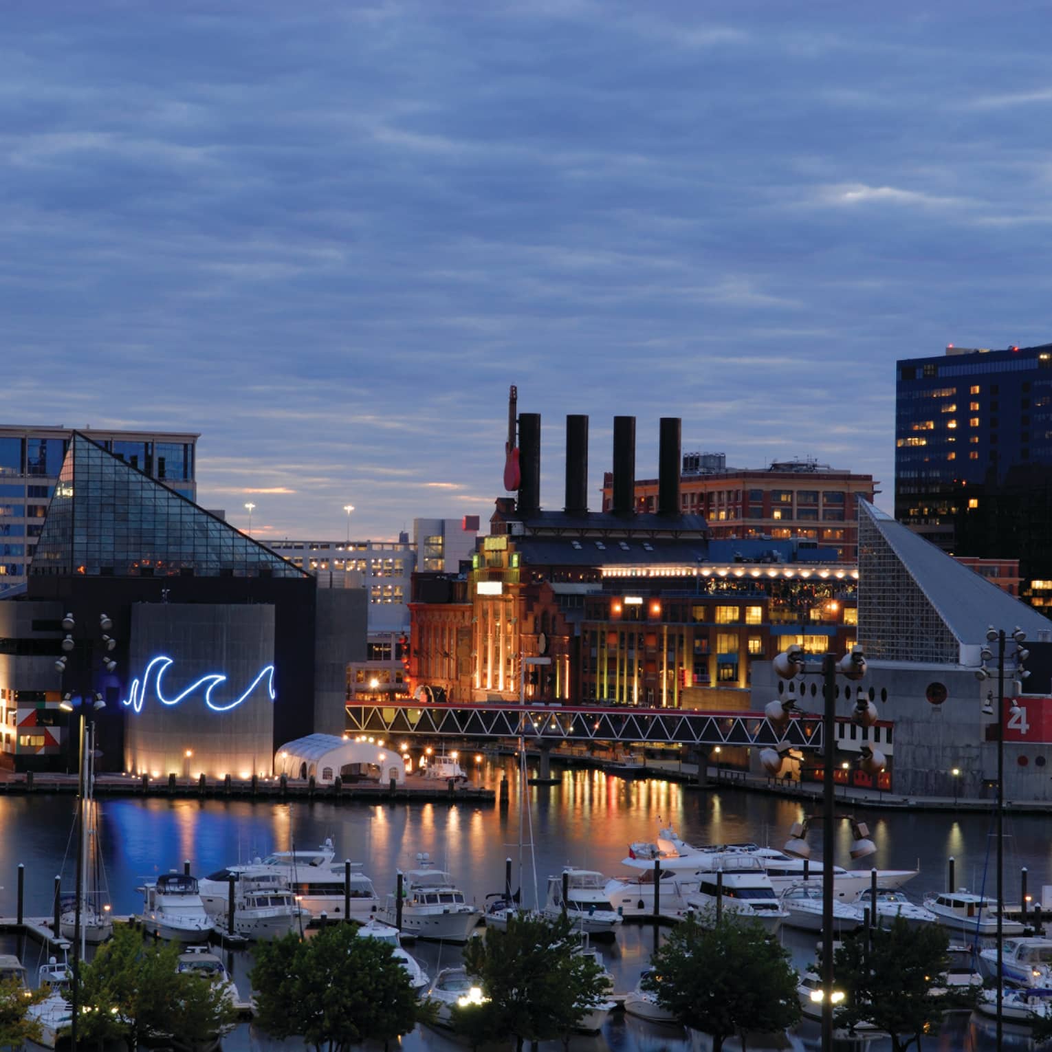 Baltimore buildings with fluorescent wave lights, boats in harbour at dusk