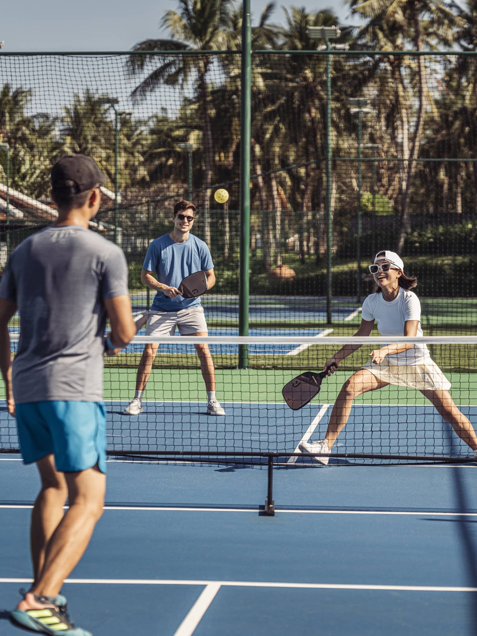 Group of 4 people play pickleball on artificial turf court