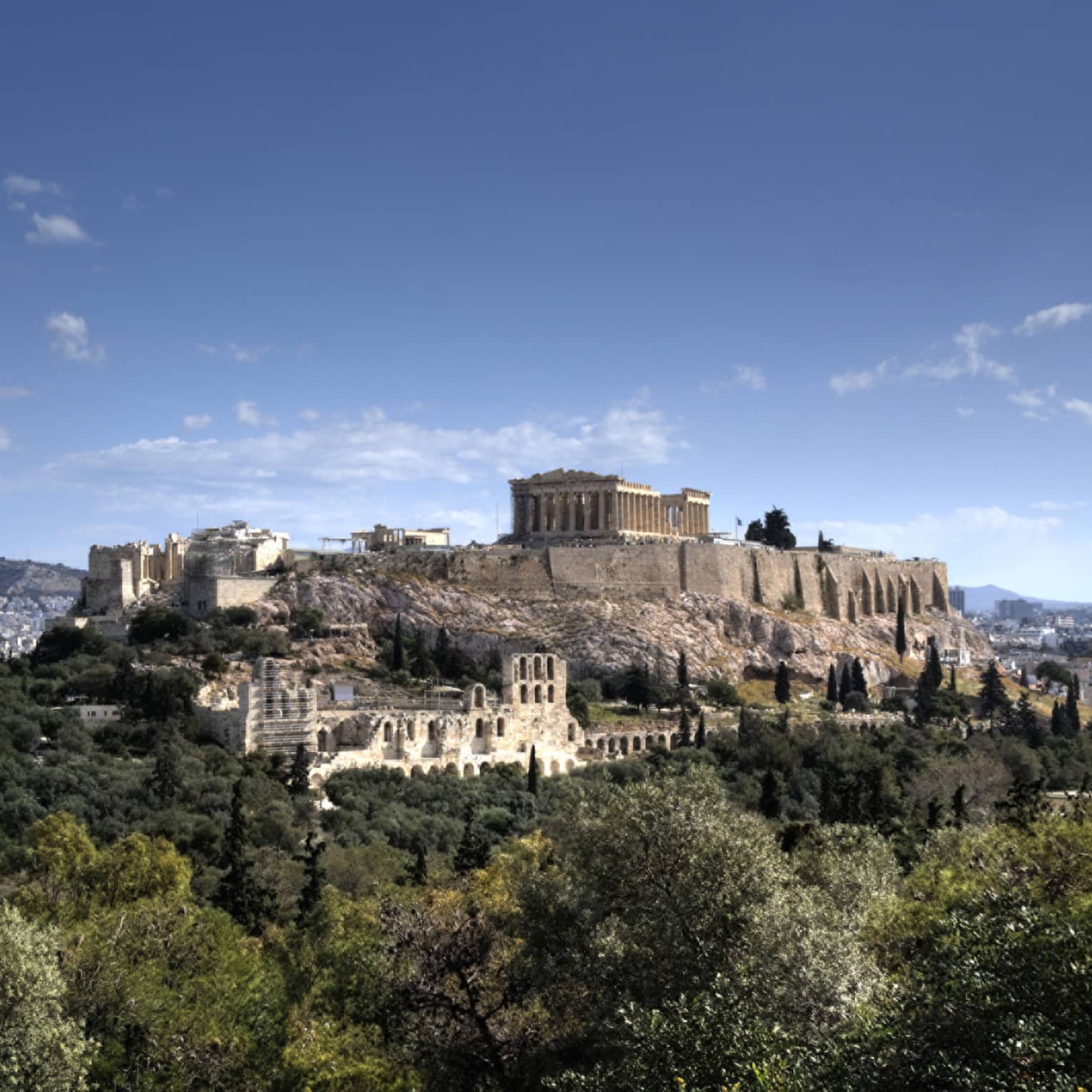 Ancient ruins of Acropolis on mountain surrounded by greenery 