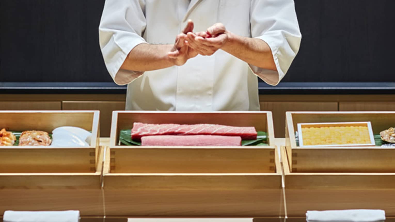 Sushi chef prepares fish behind bamboo display, Sushi wakon bar