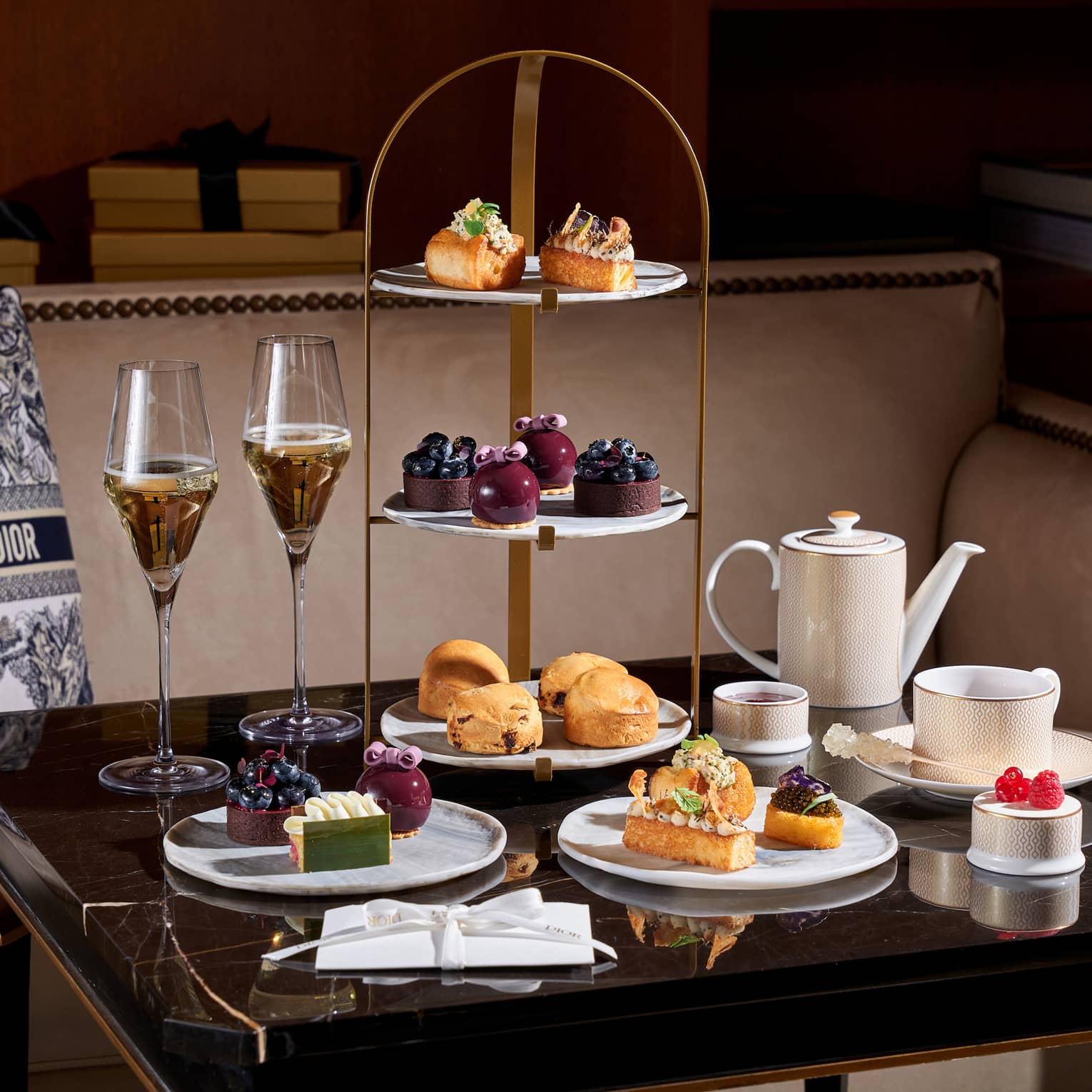 Christmas afternoon tea setup on square table beside banquette set with a black-and-white Christian Dior pillow