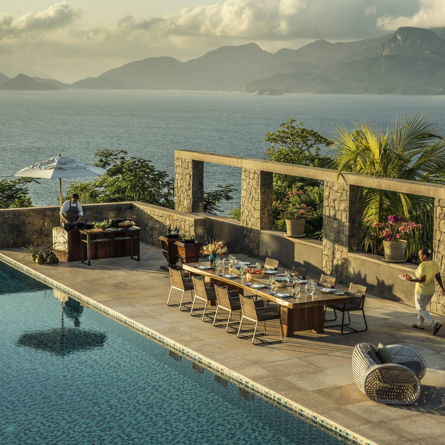 Aerial view of Four-Bedroom Residence Villa private deck with 8-person dining table beside pool, ocean view