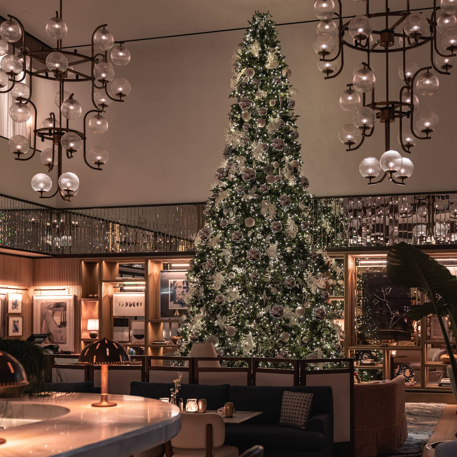 Restaurant with high ceilings and large chandeliers displaying a massive Christmas tree