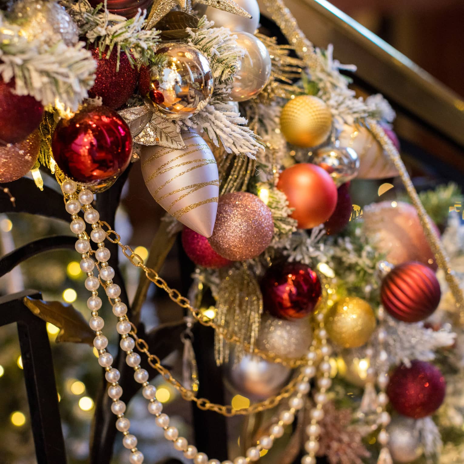Red and gold ornaments placed on garland on a staircase