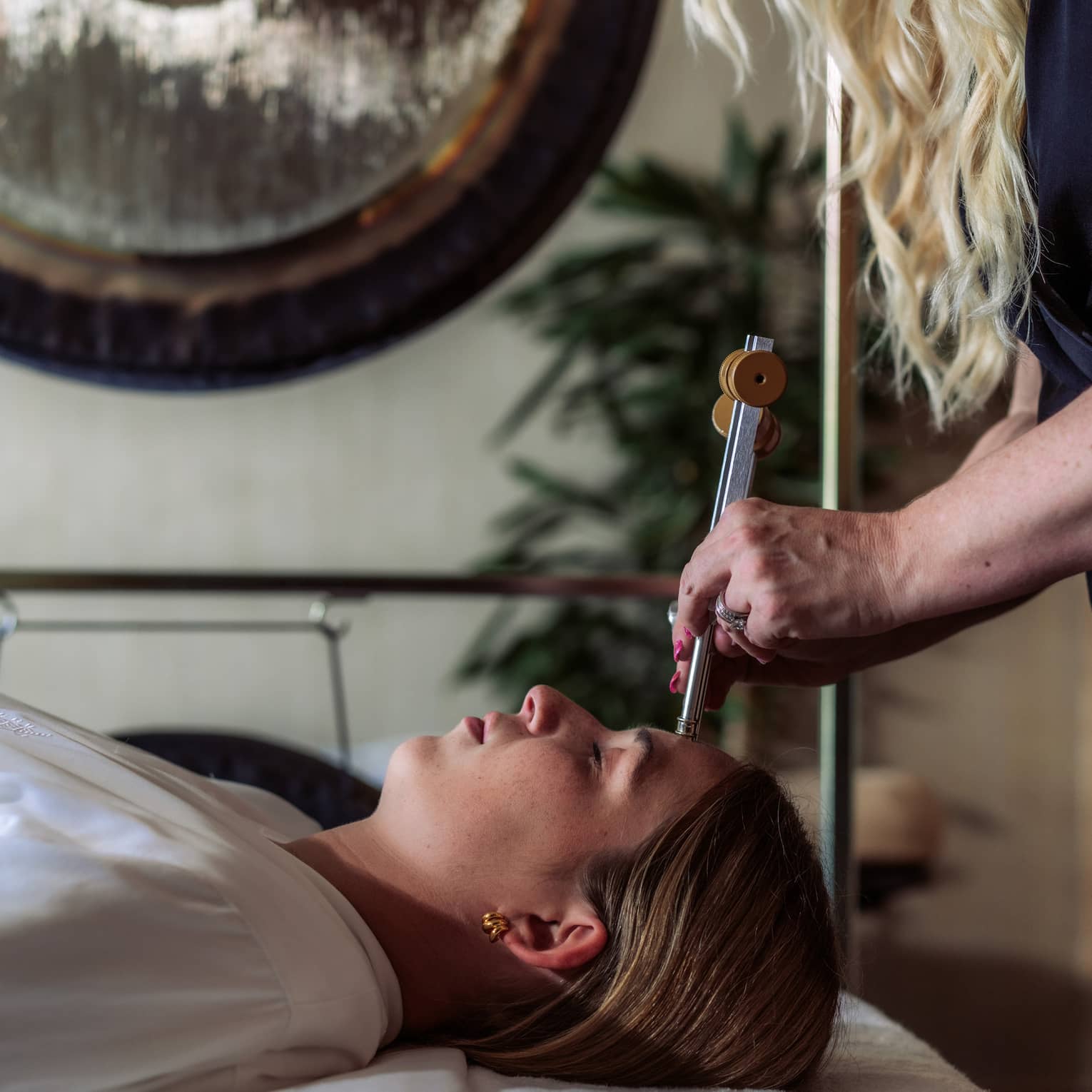 A woman receiving sound healing treatments at a spa.