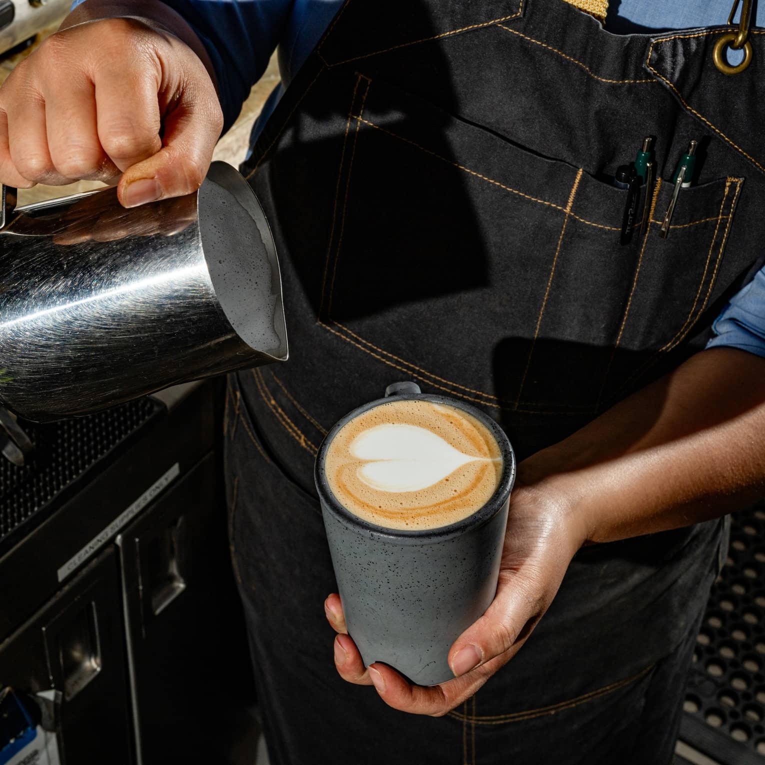 A person pouring milk in a mug of coffee