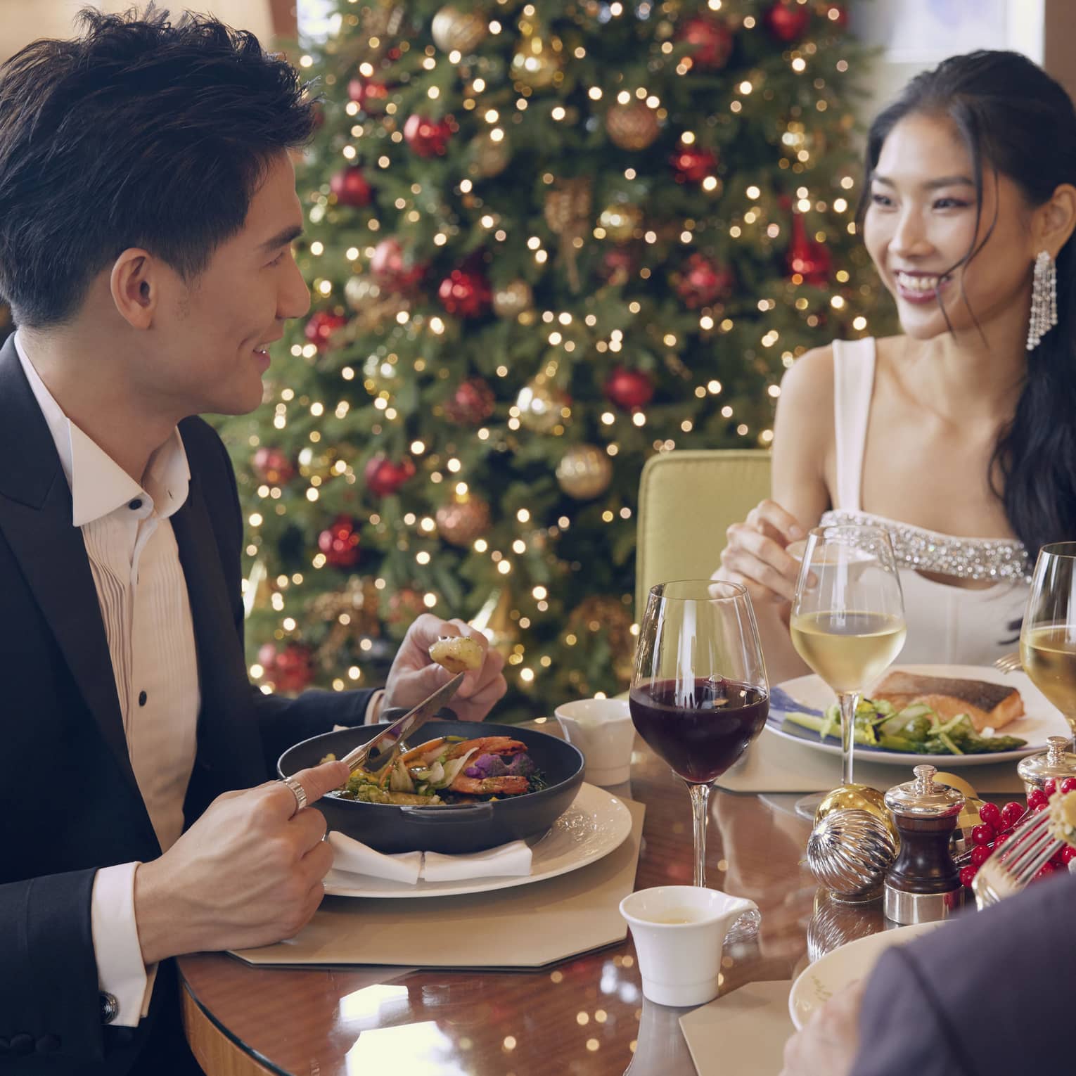 Man and woman dine at restaurant with Christmas tree in the background