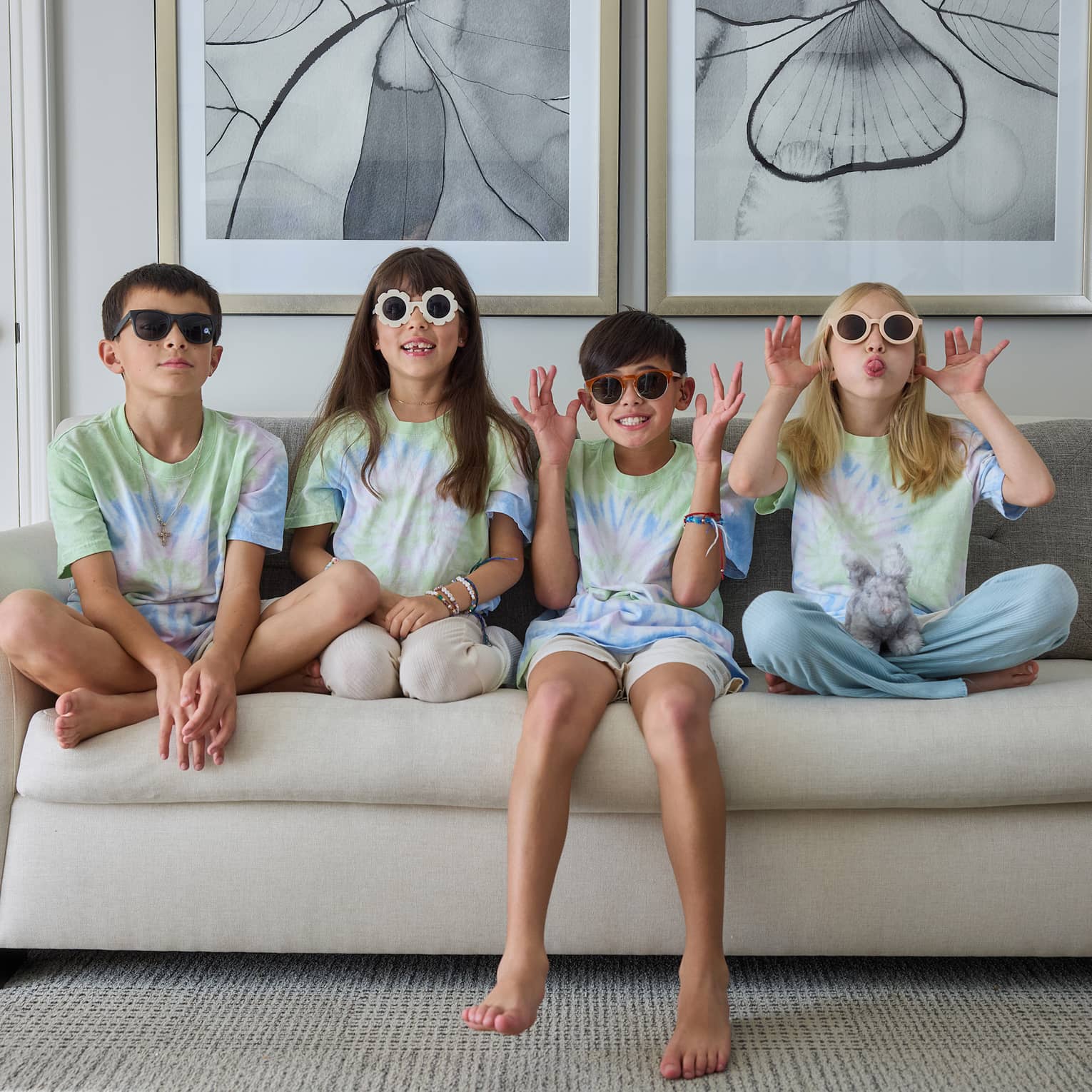 Four young guests sitting beside each other on a couch and wearing sunglasses