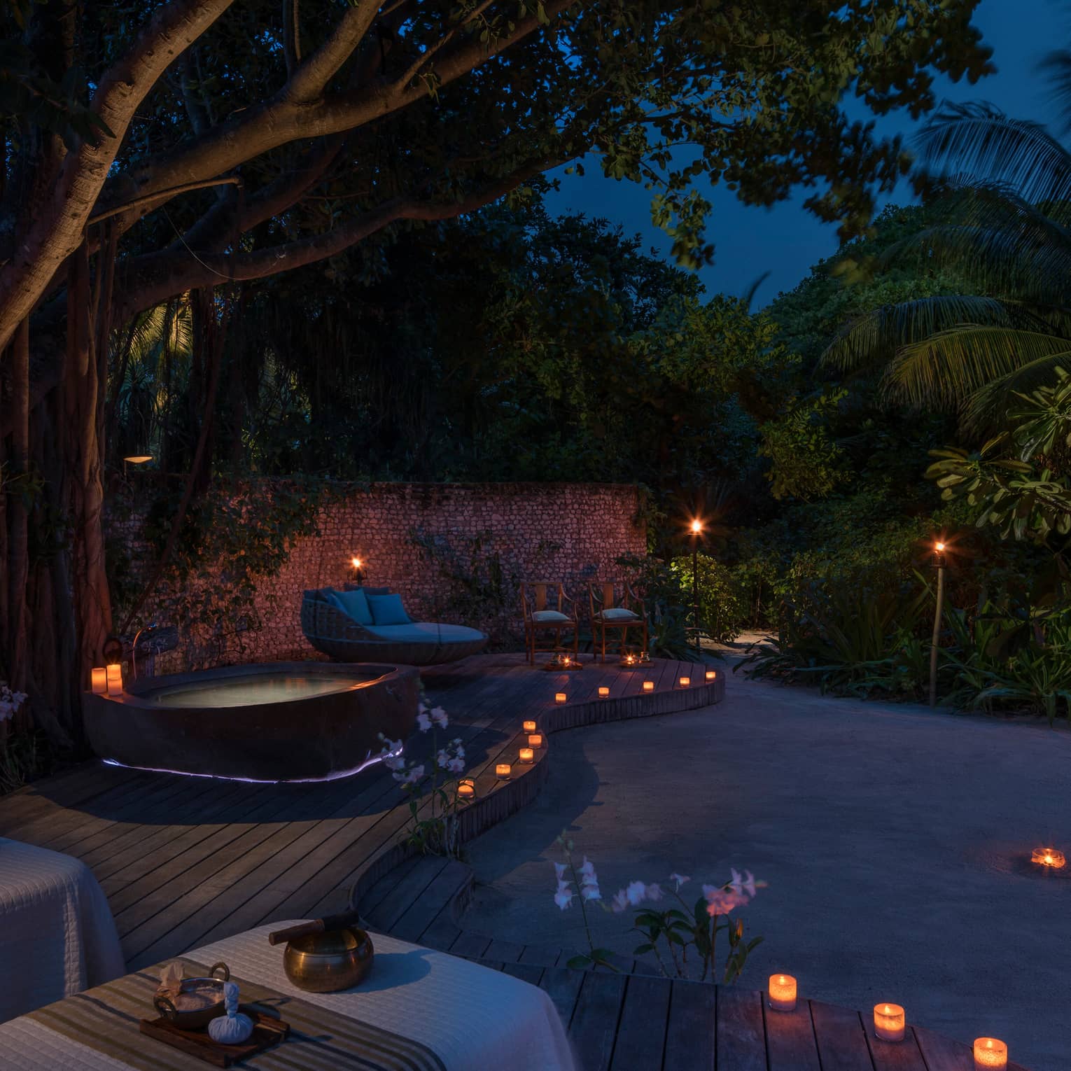 Candles along sand beach, spa patio, hot tub at night