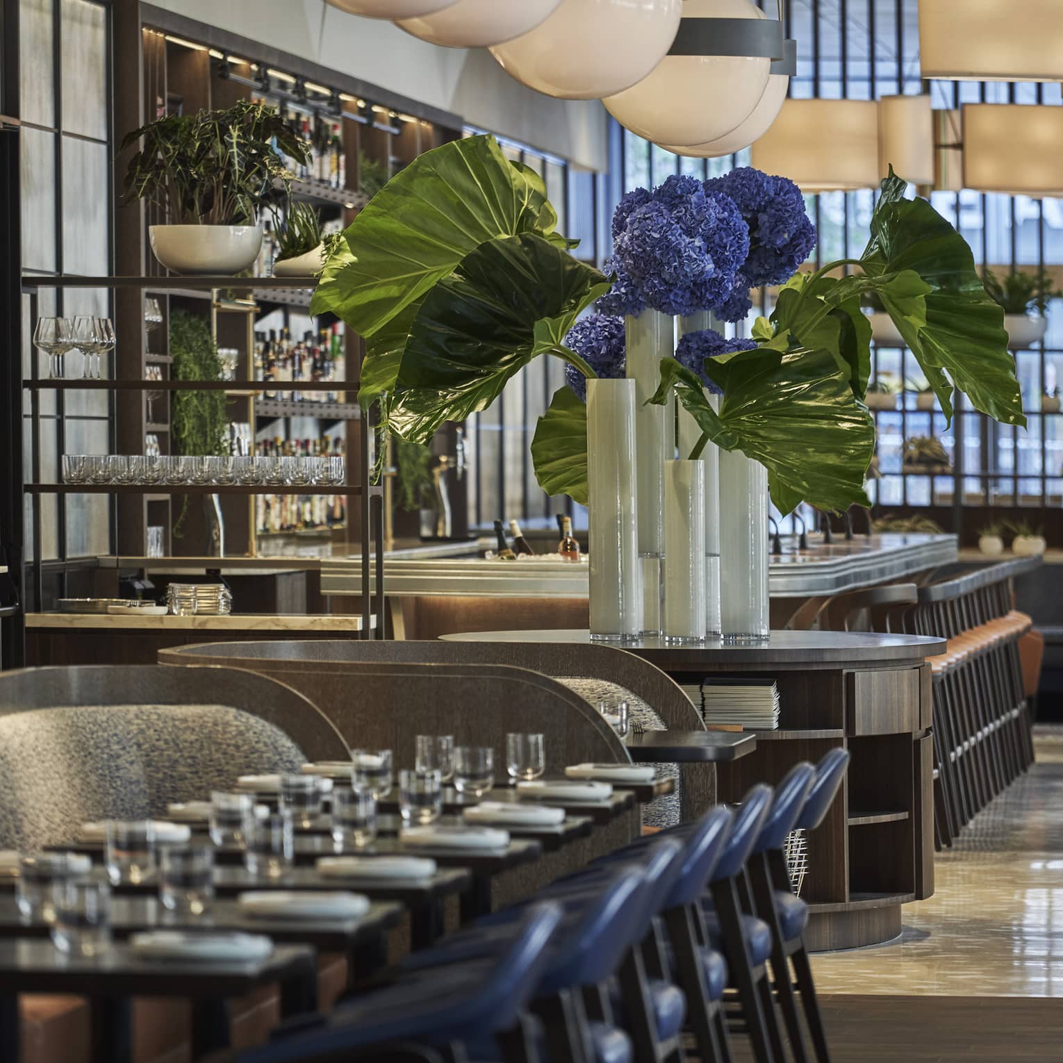 A long table is set with white porcelain plates and clear glasses at Vernick Restaurant in Four Seasons Philadelphia