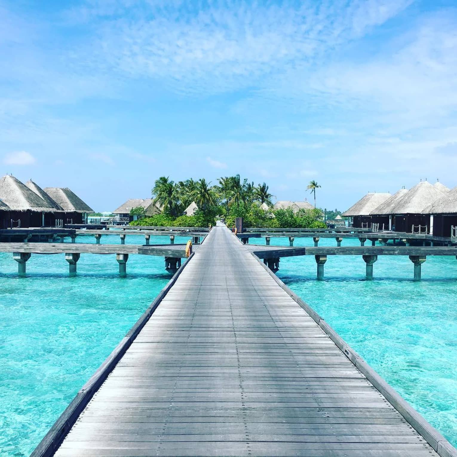 Long boardwalk stretched over lagoon leading to overwater bungalows