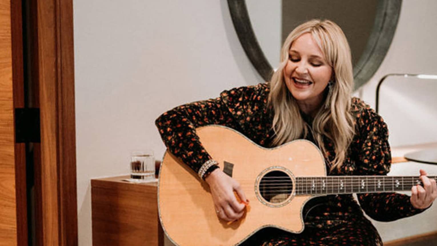 Woman sings a song with a guitar for guests in a hotel suite
