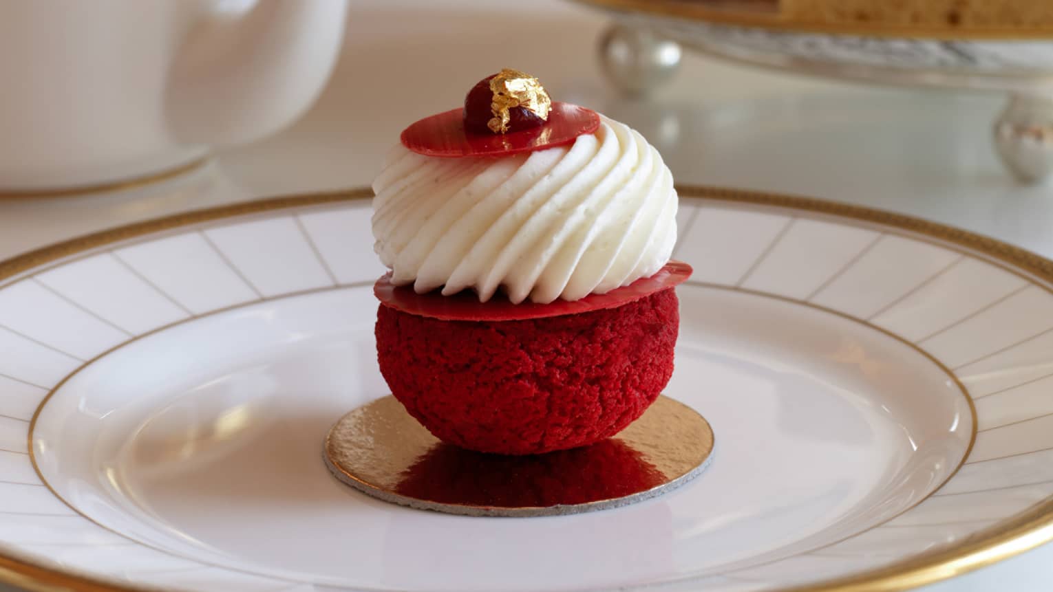 Afternoon tea at Rotunda Lounge serves red cream-topped pastry on white and gold plate
