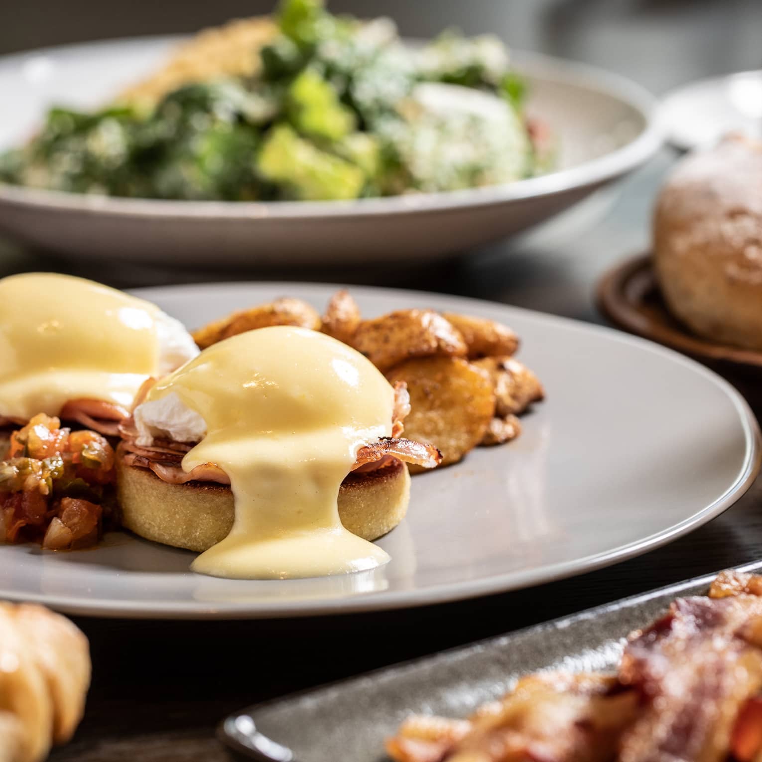 Sunday brunch table with Eggs Benedict, bacon and salad