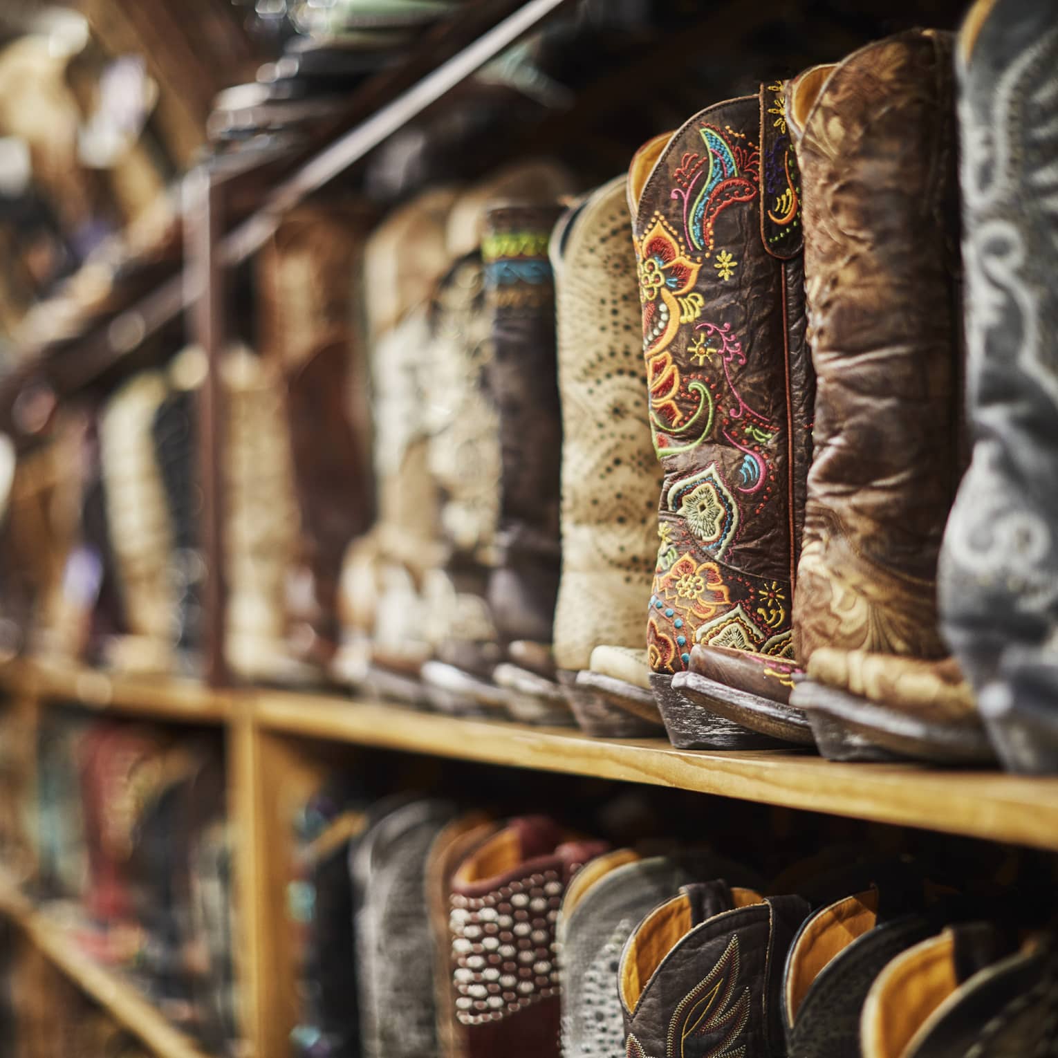 Shelves of cowboy boots of varying colours including black, brown and beige.