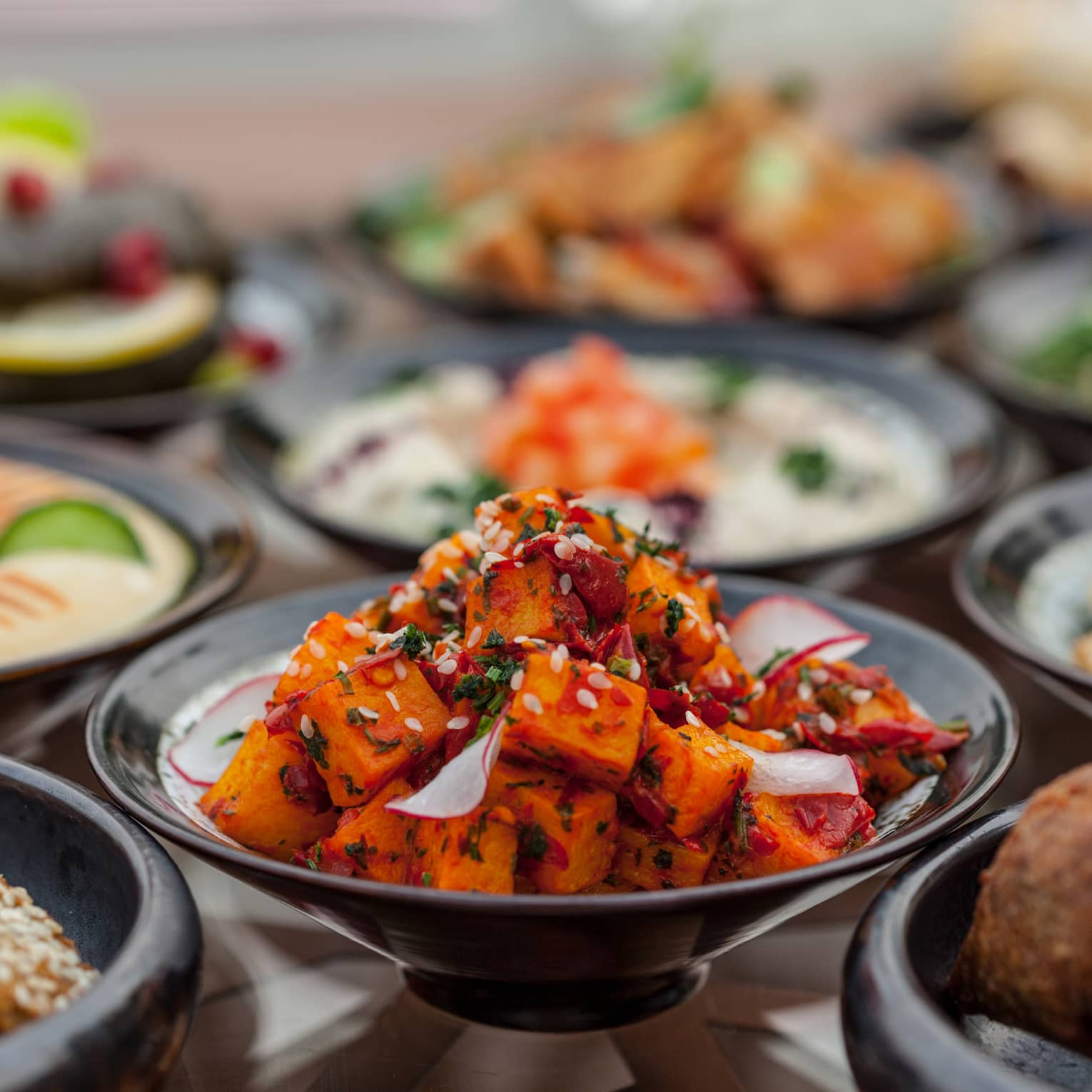 Several black plates filled with meat and vegetable appetisers.