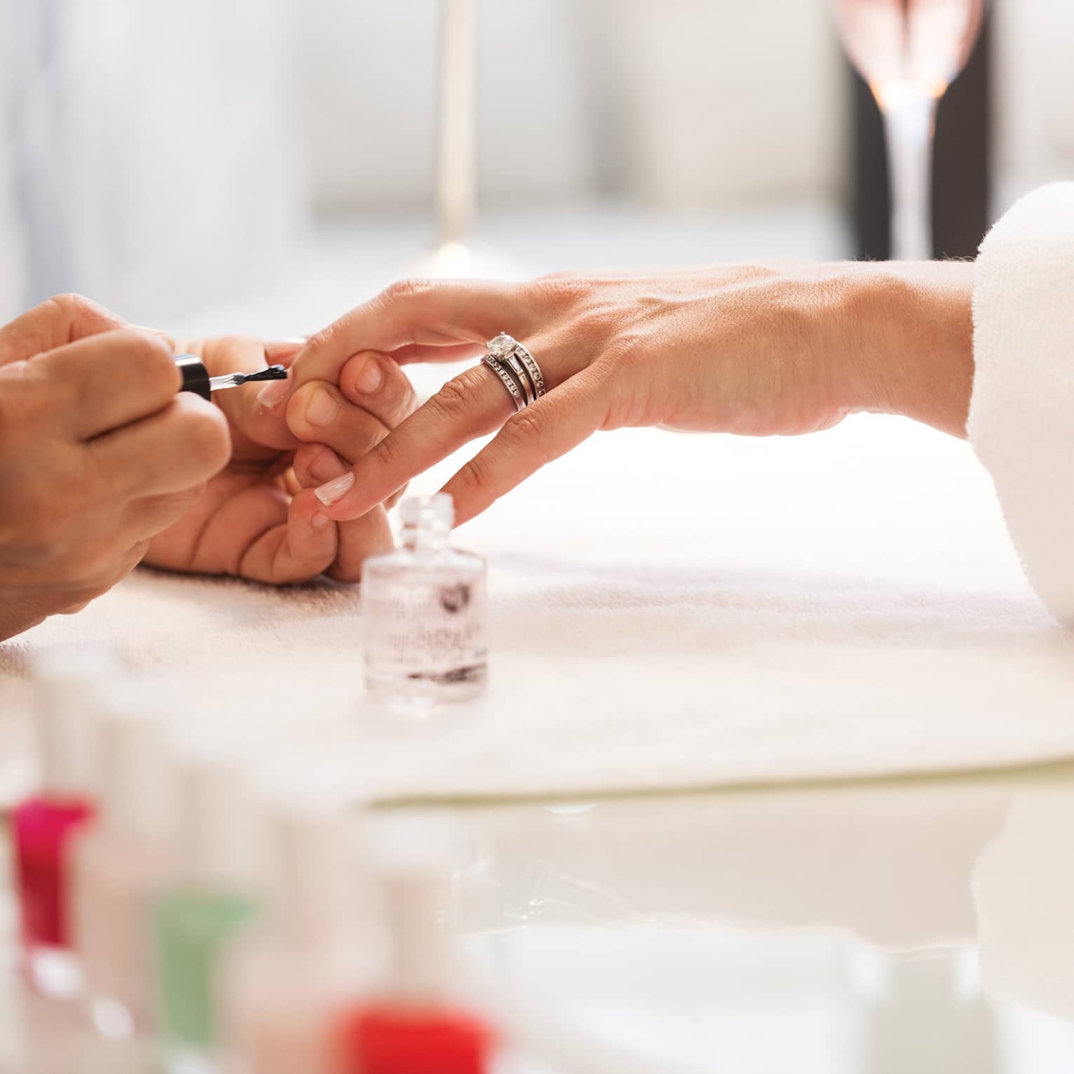Close-up of woman in white robe getting clear polish manicure at spa table