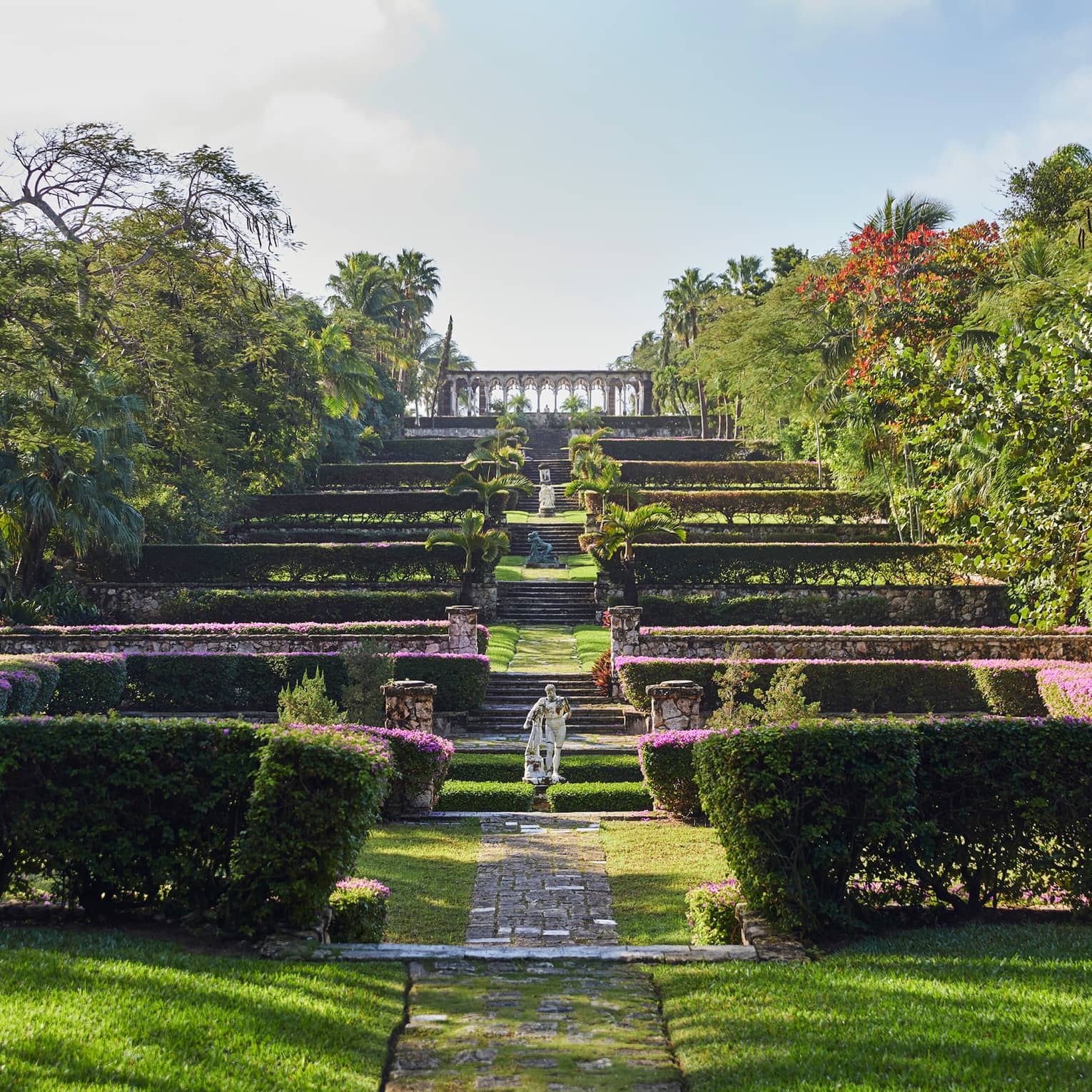 Statues on steps of hedges, manicured gardens