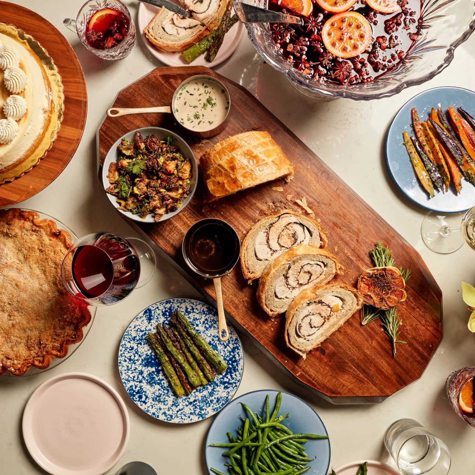 An assortment of Thanksgiving food, including pie, vegetables, bread and ham.