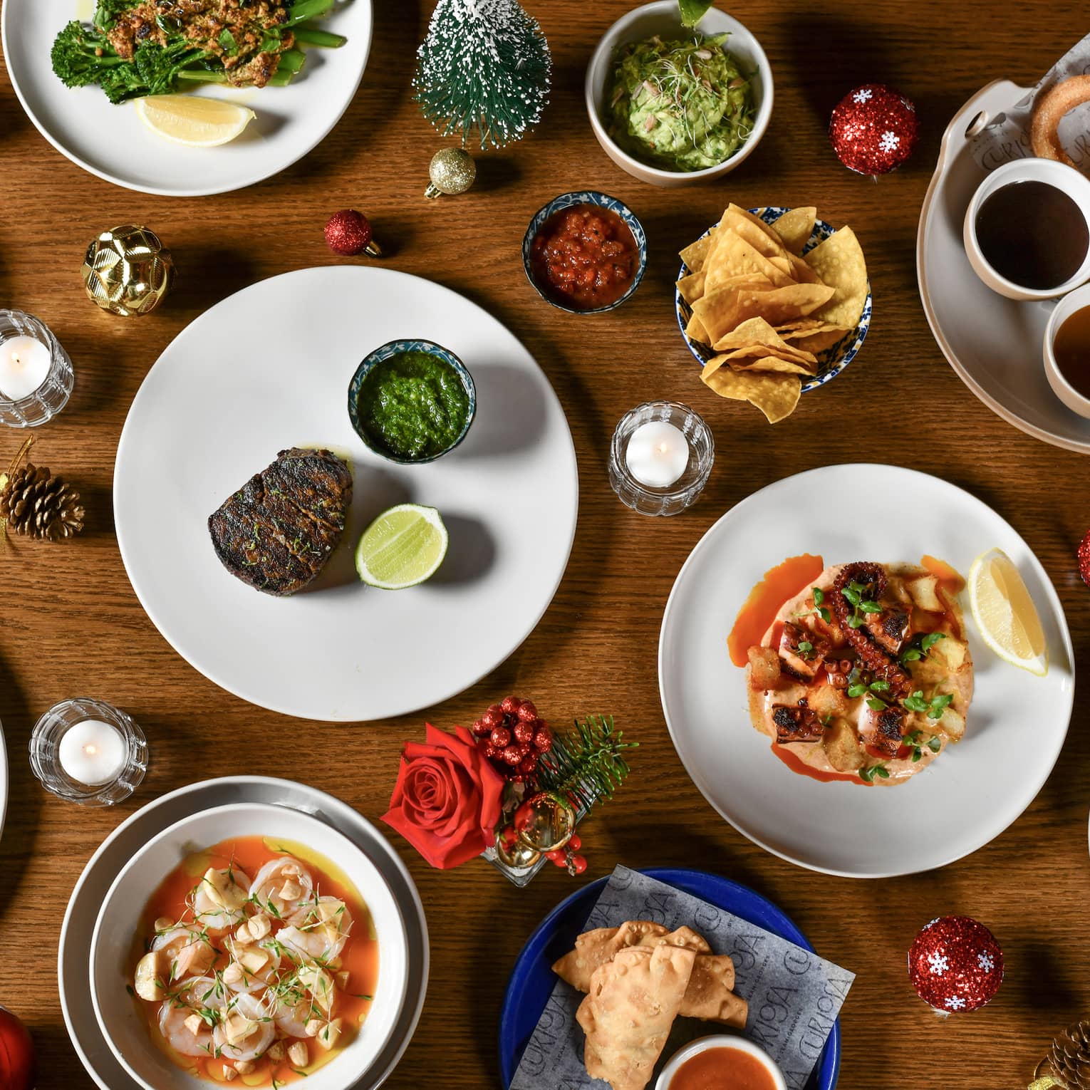 Overview of a wooden table filled with a variety of dishes along with festive ornaments and pinecone decorations