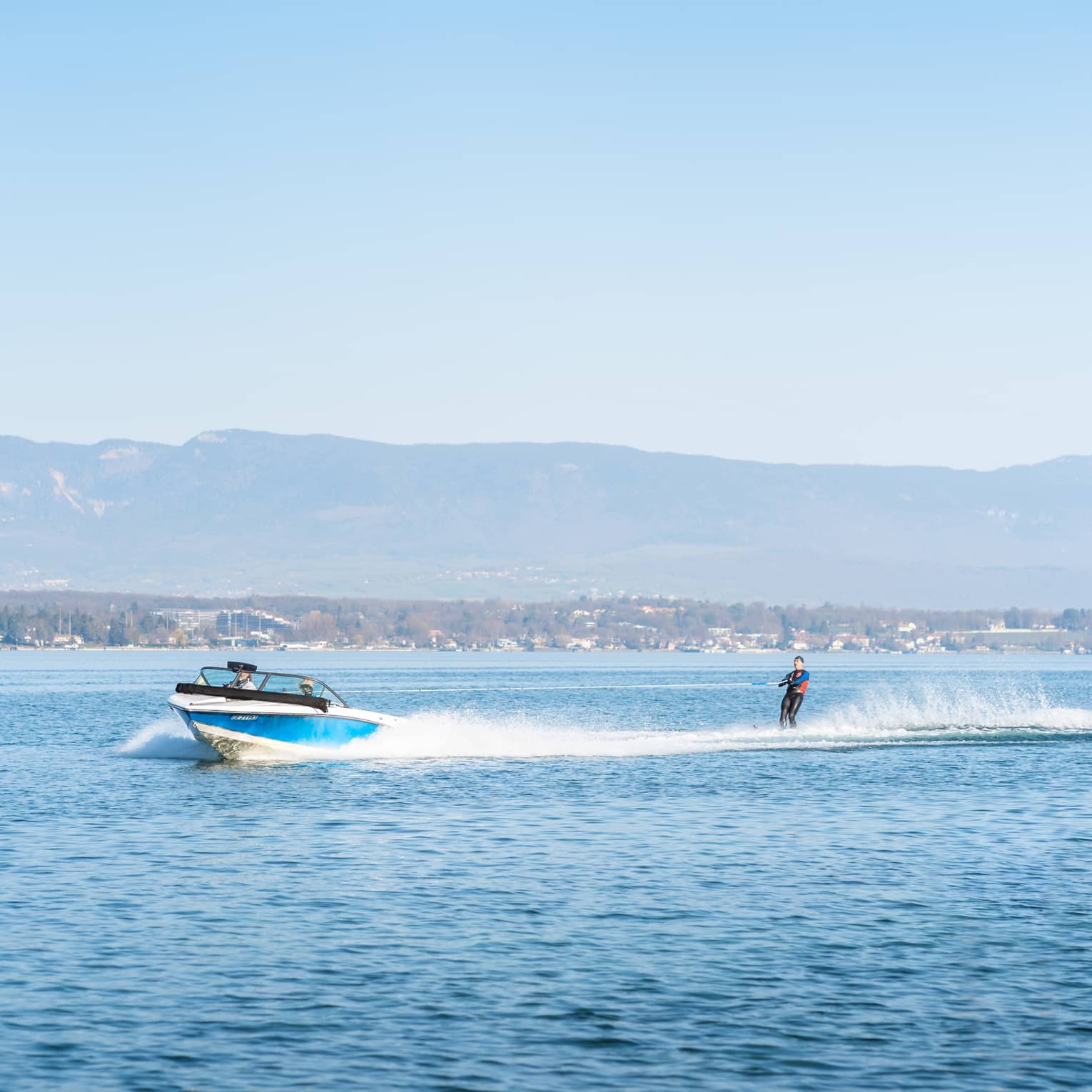 Blue-and-white boat pulling waterskiier on Lake Geneva