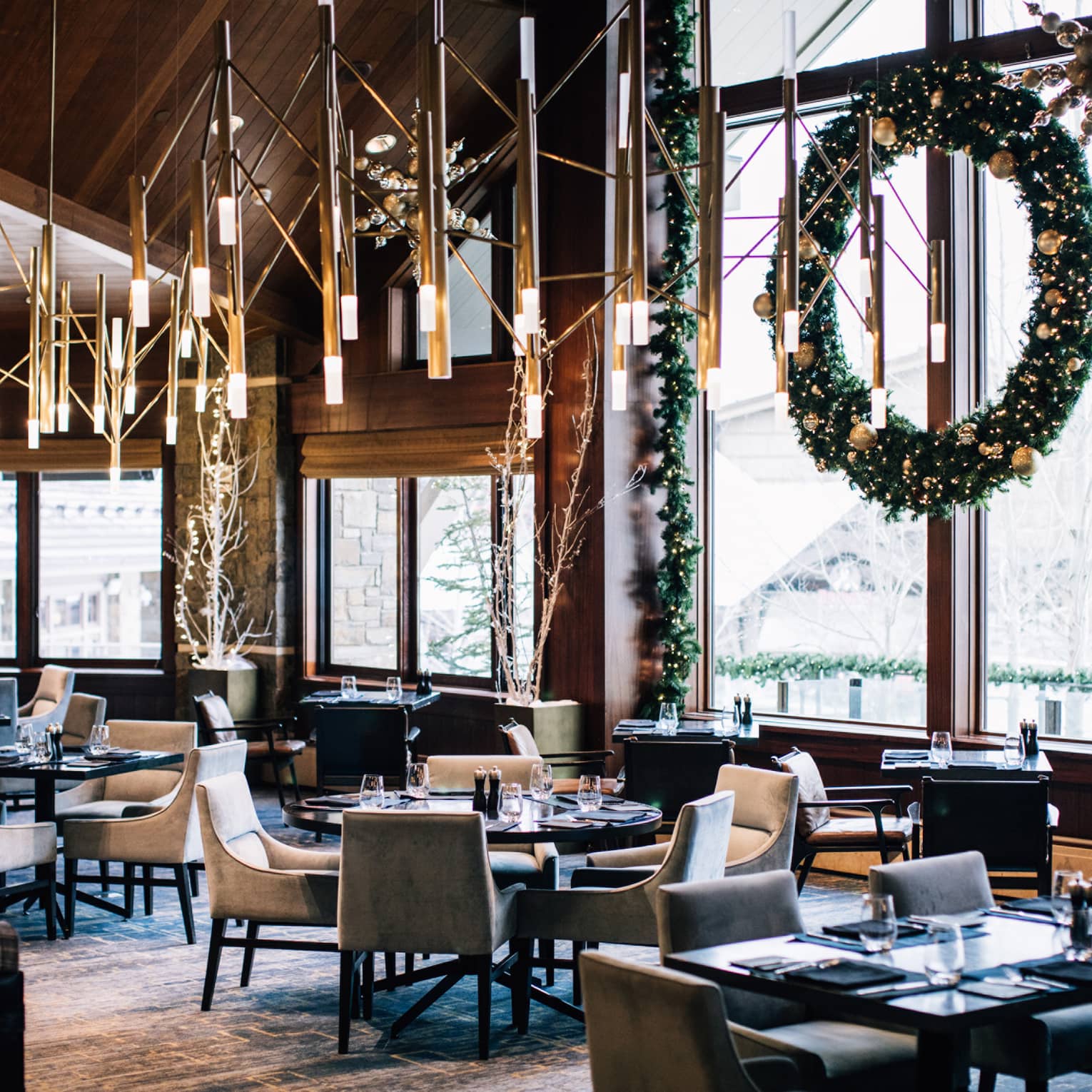 The inside of a restaurant with holiday decorations and snow visible through a large window.