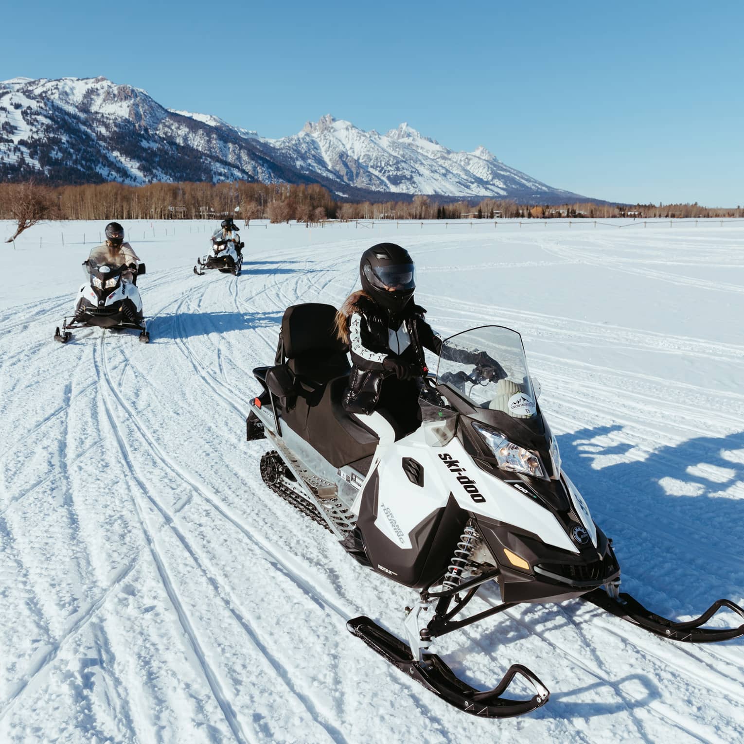 Three people on snowbmobiles.