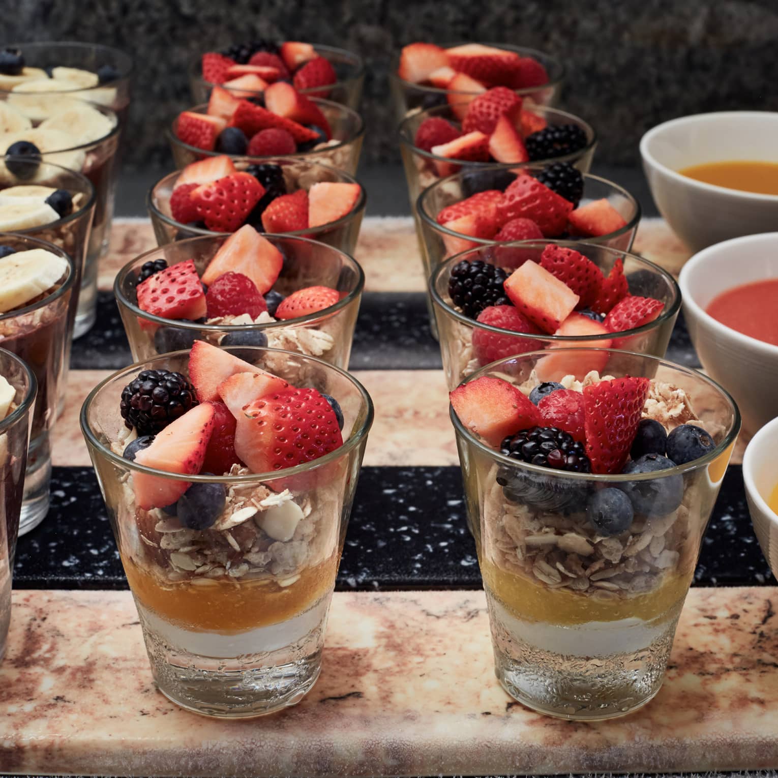 Yogurt and fruit parfait shooters lined up on a brunch buffet display