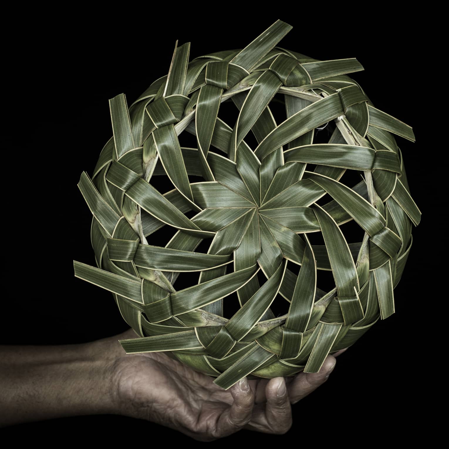 A hand holding a spinning wheel of palm fronds.