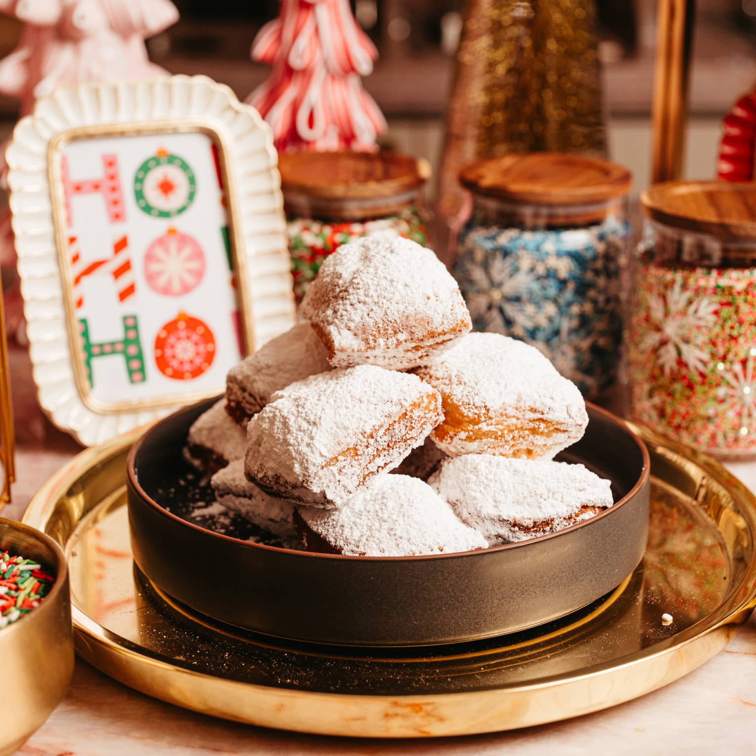 A bowl of desserts with a bowl of sprinkles beside it and festive d�cor.