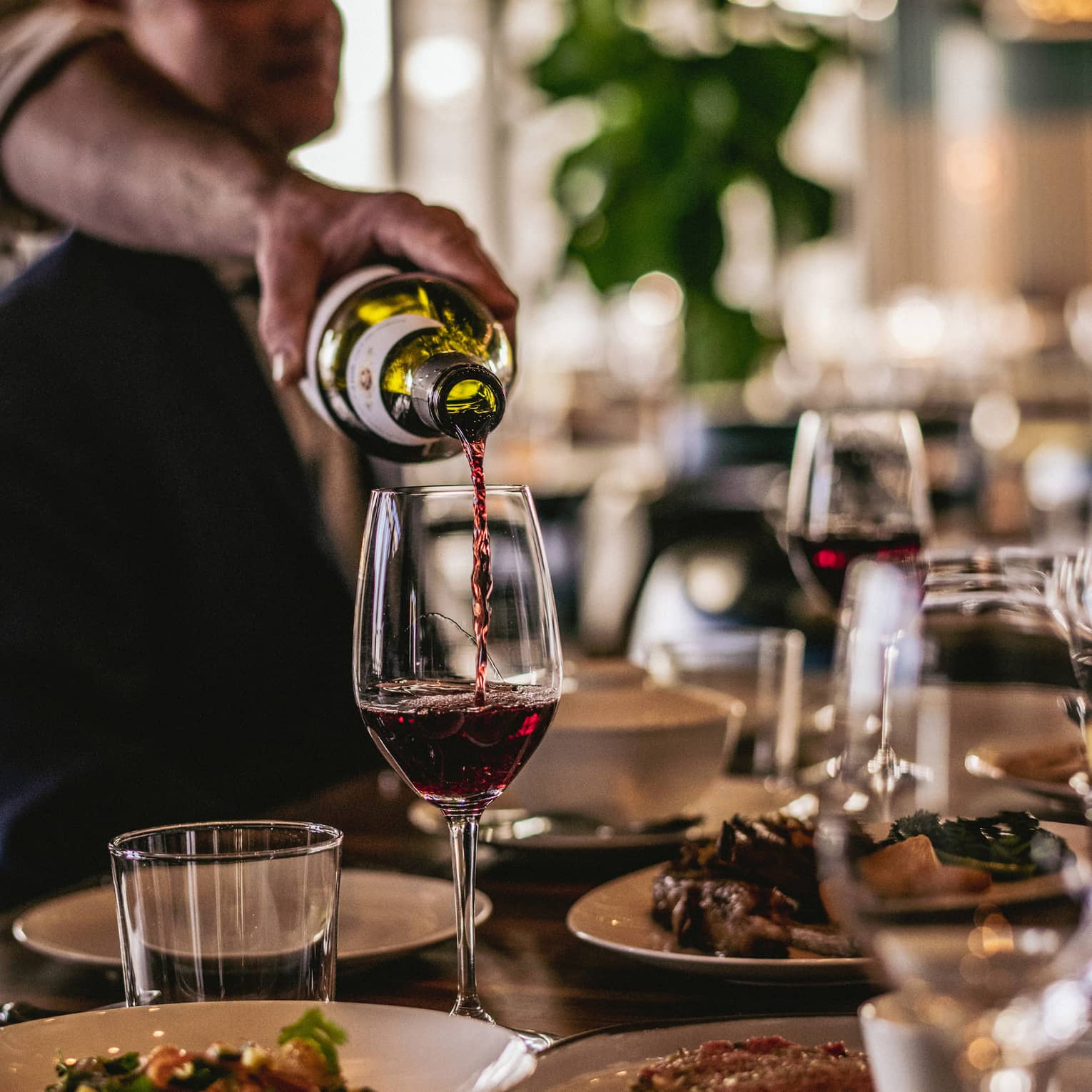 A server pouring a glass of wine.