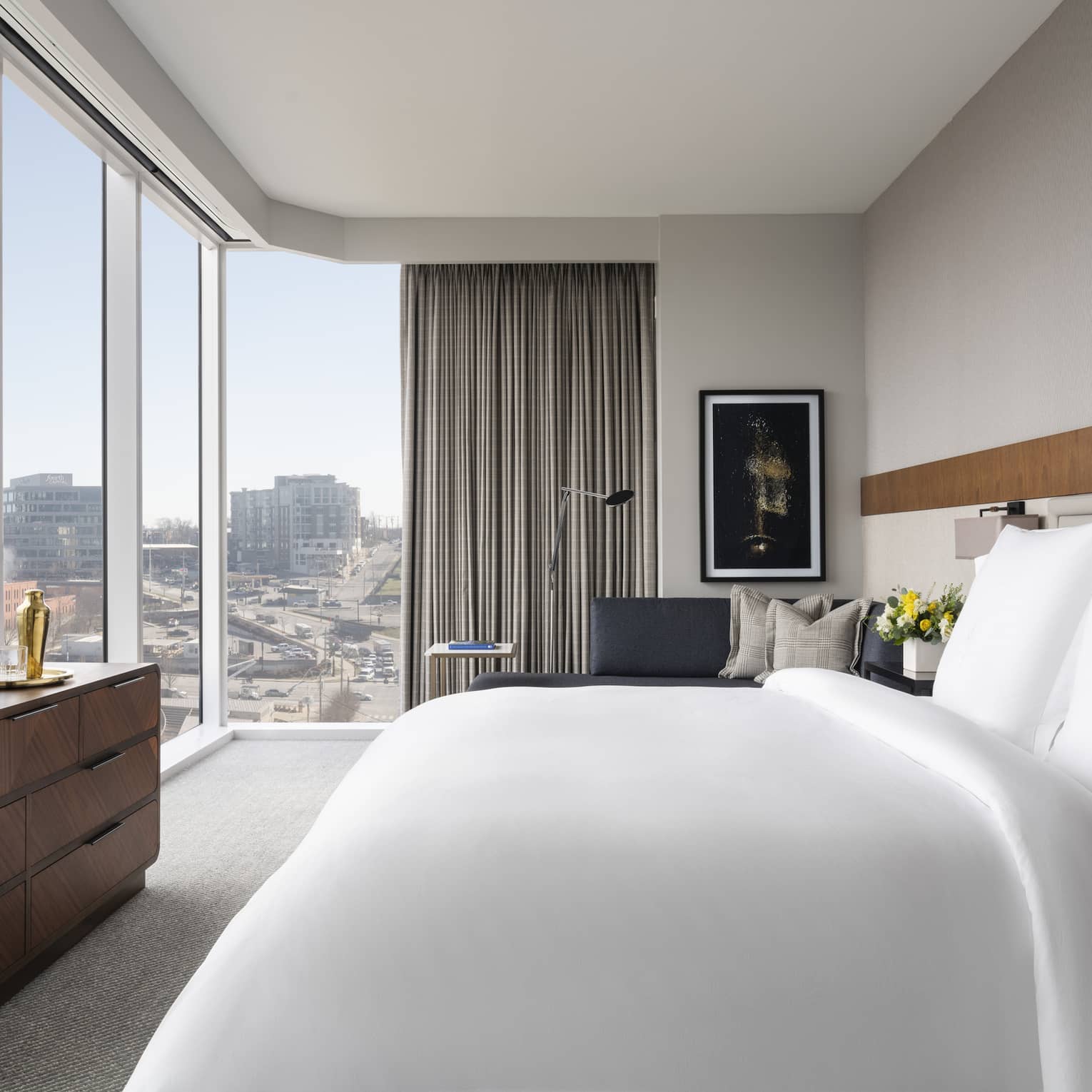 Hotel room with king bed looking out to corner-view wall of windows