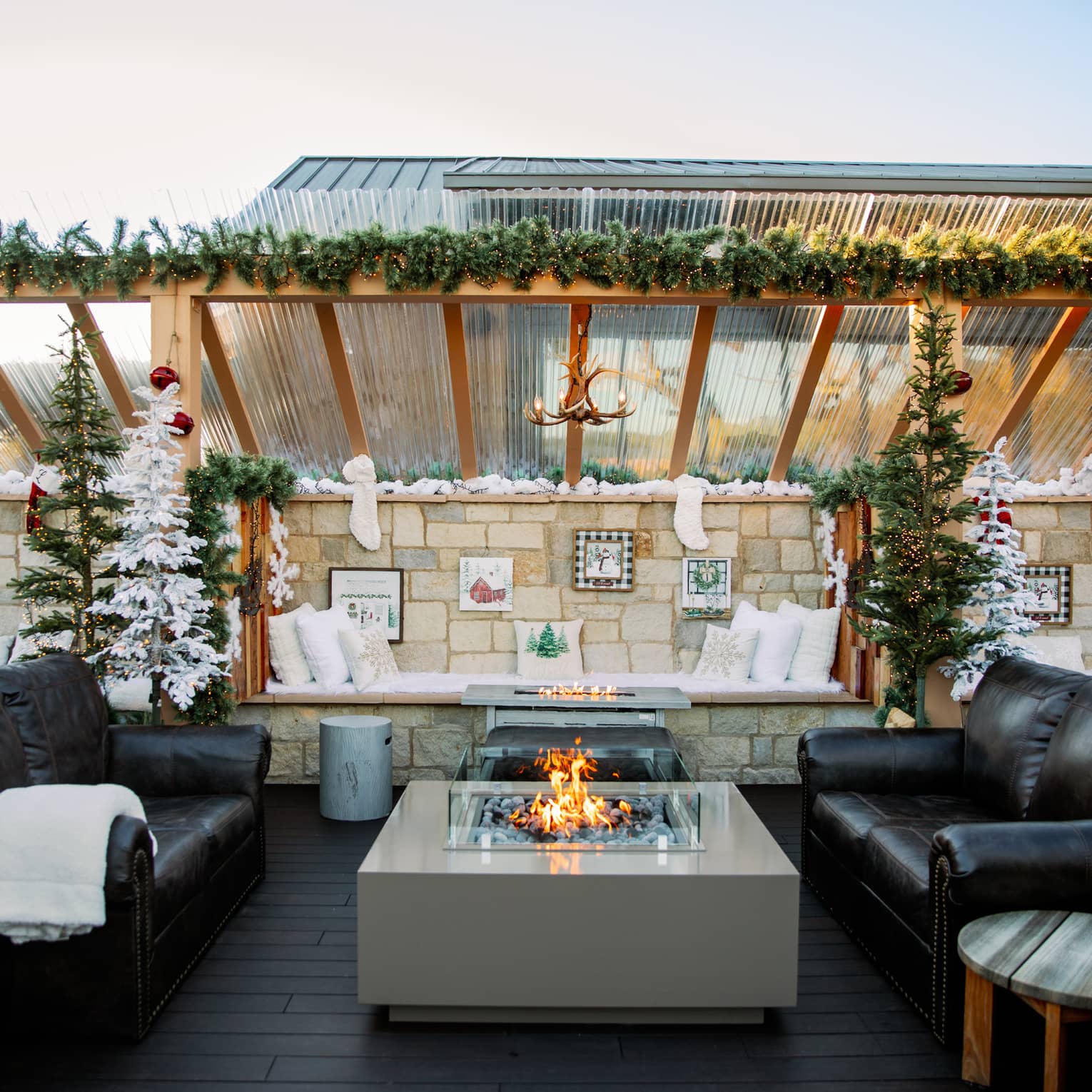 Outdoor terrace with two couches and a fire pit, and festive decorations.