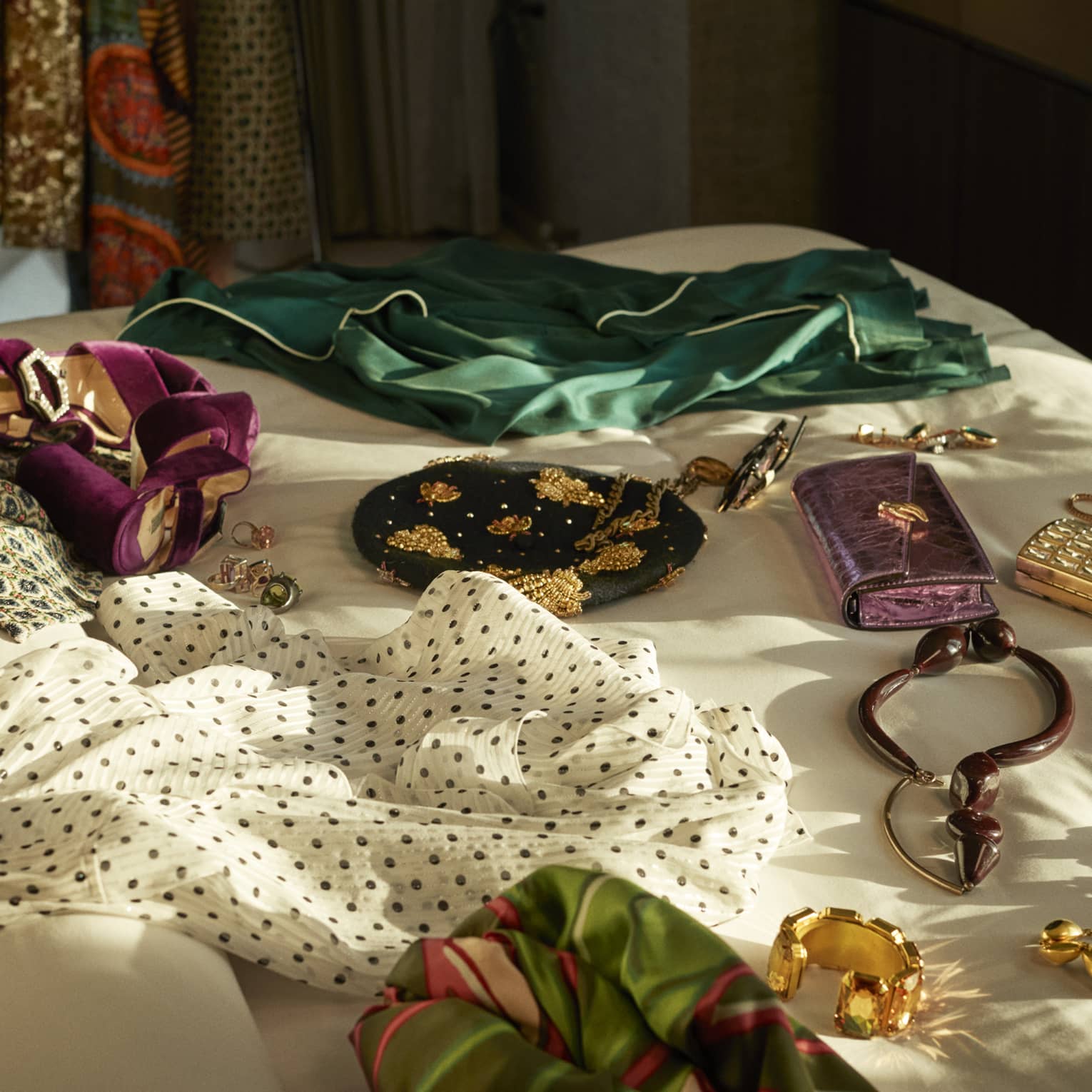 Clothes, gold jewelry and wallets spread out on bed.
